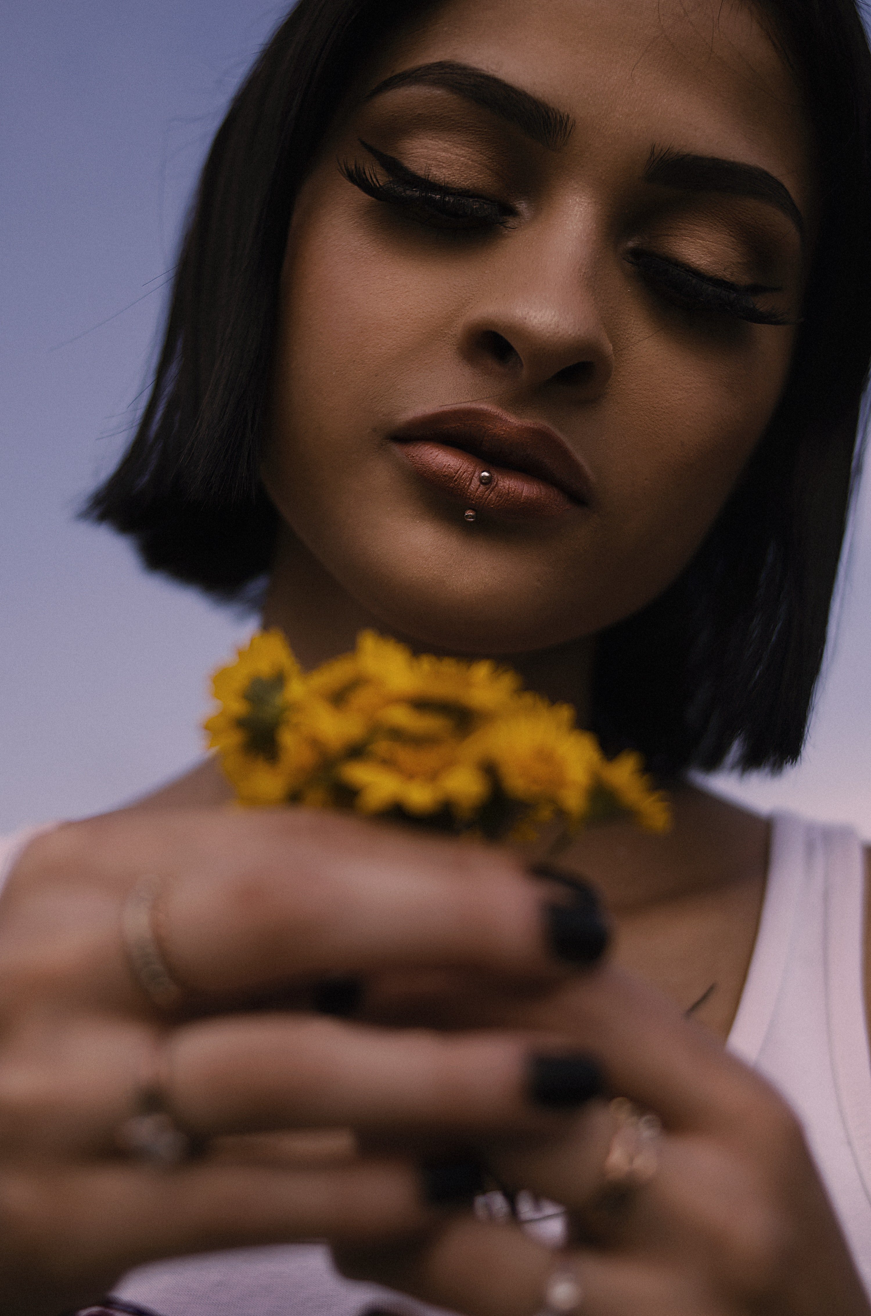 Woman with labret piercing holding yellow flowers | Source: Pexels.com/Juan Ló
