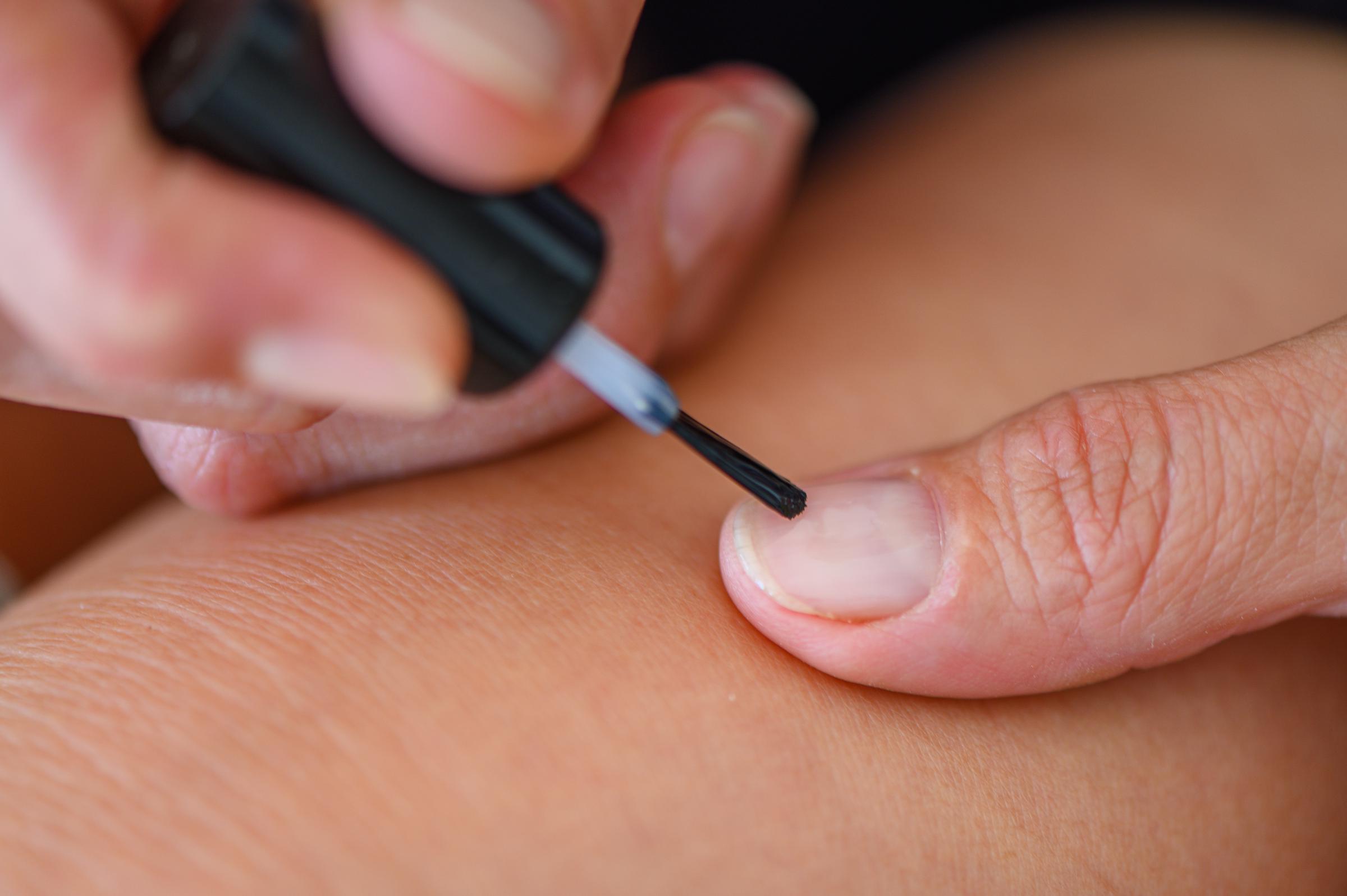 Woman covering her nails with colorless varnish | Source: Shutterstock
