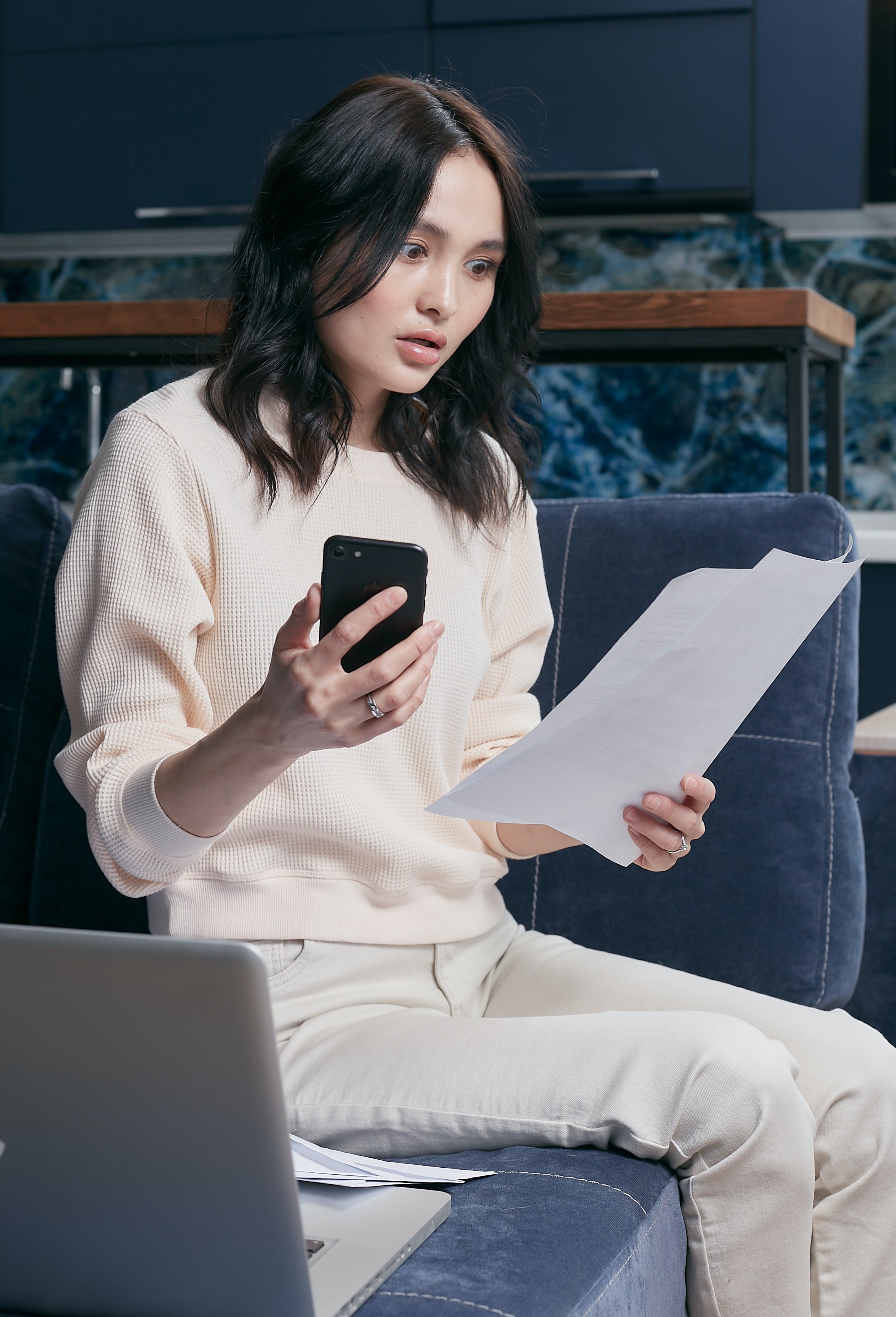A woman looking stunned from starring at a document while holding a phone | Source: Pexels