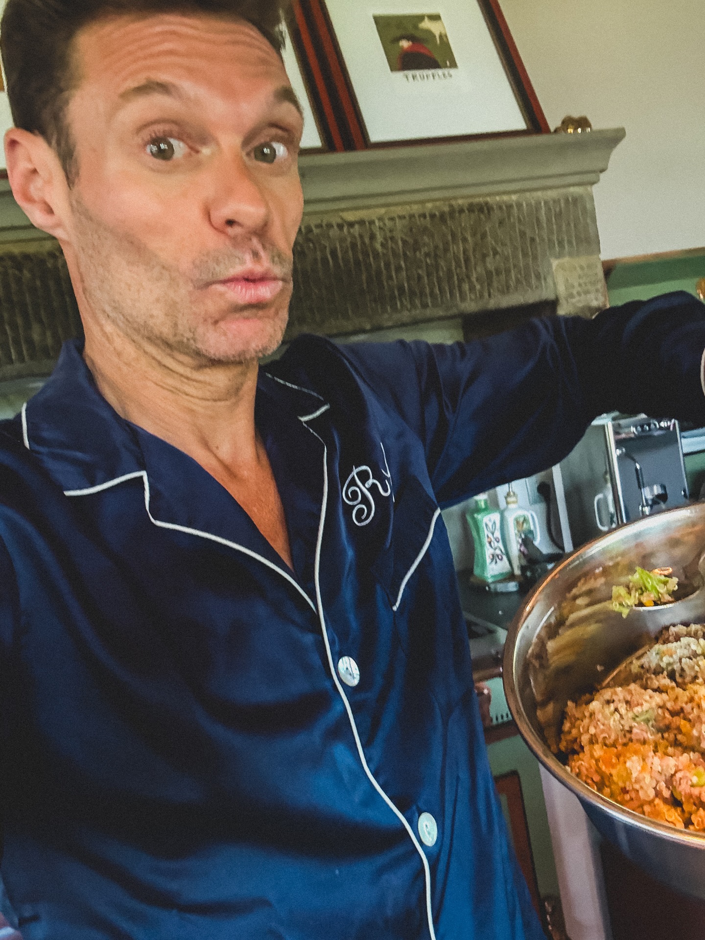 Ryan Seacrest poses in navy pajamas while holding a bowl of dog food, posted on June 30, 2025 | Source: Instagram/ryanseacrest
