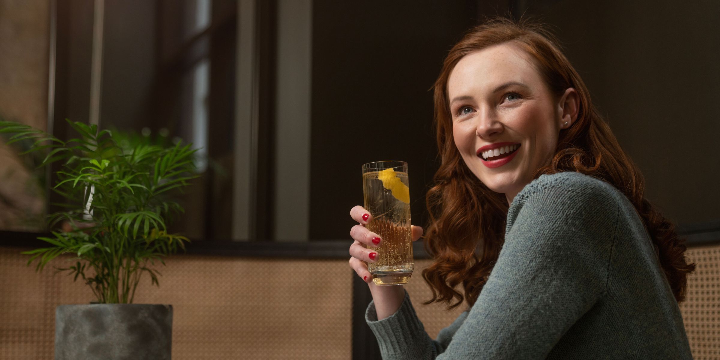 A smiling woman holding a cocktail drink | Source: Pexels