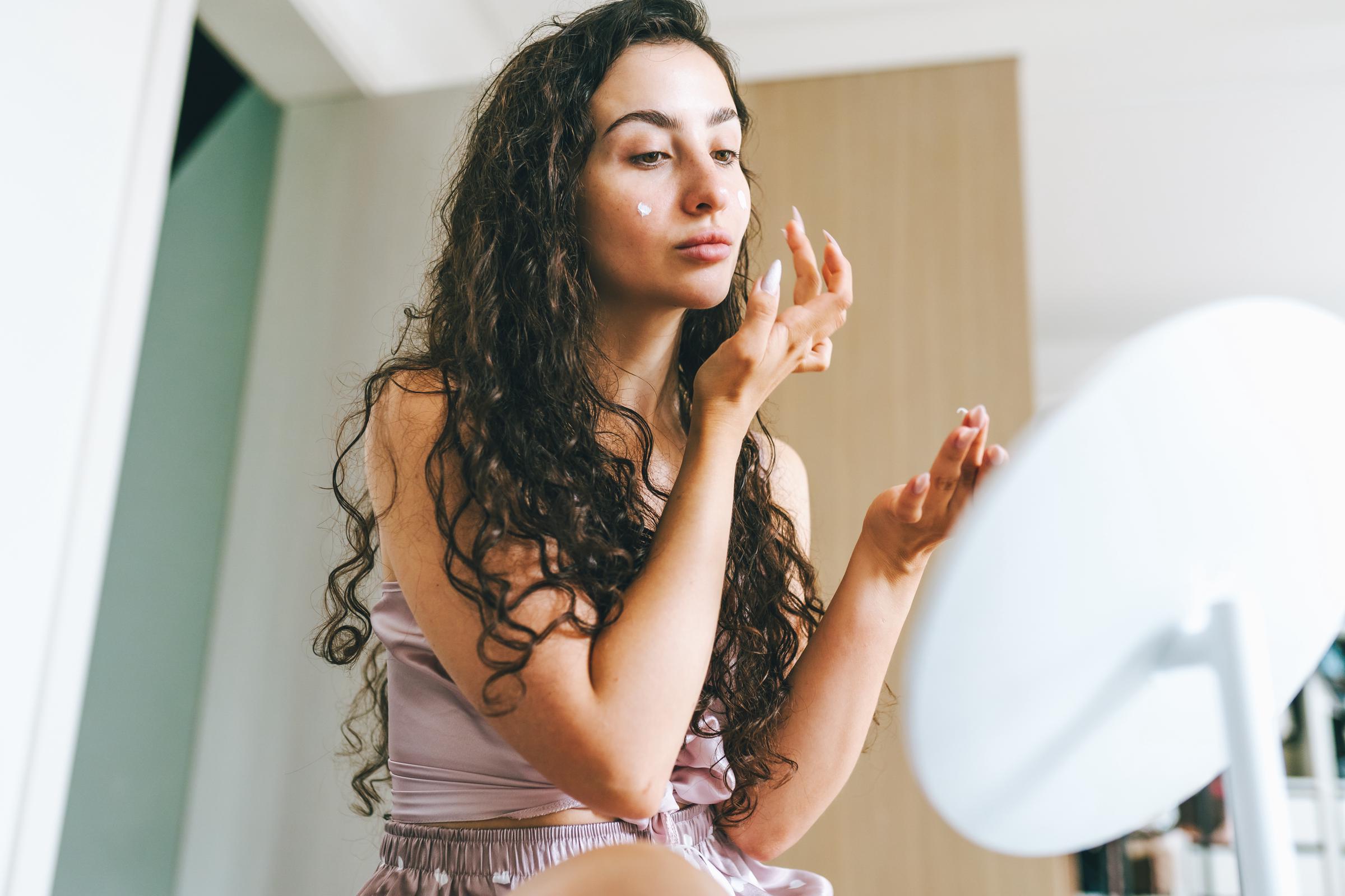 A woman applying cream in her mirror | Source: Getty Images