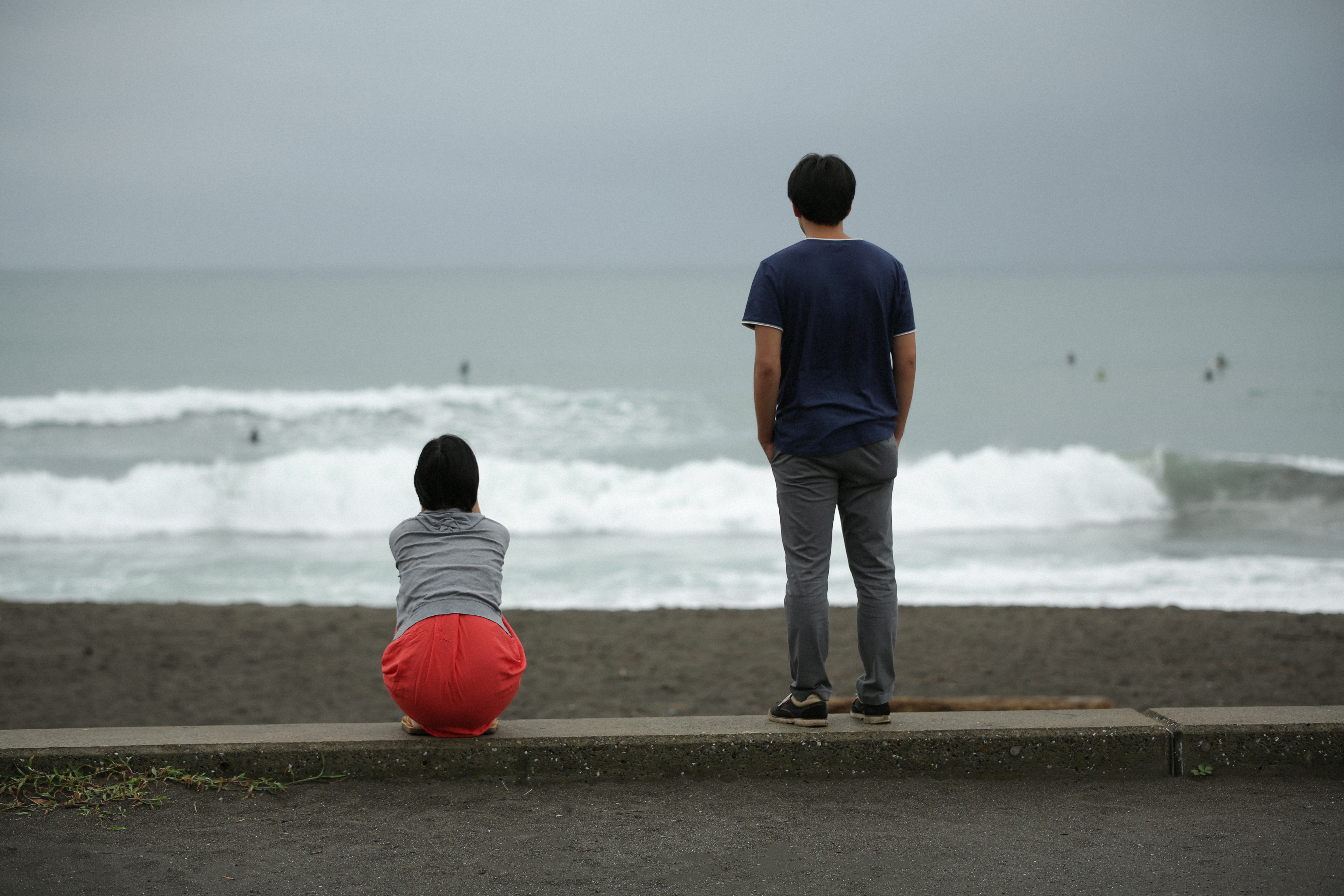 A couple watching the ocean waves with their backs to the camera | Source: Getty Images