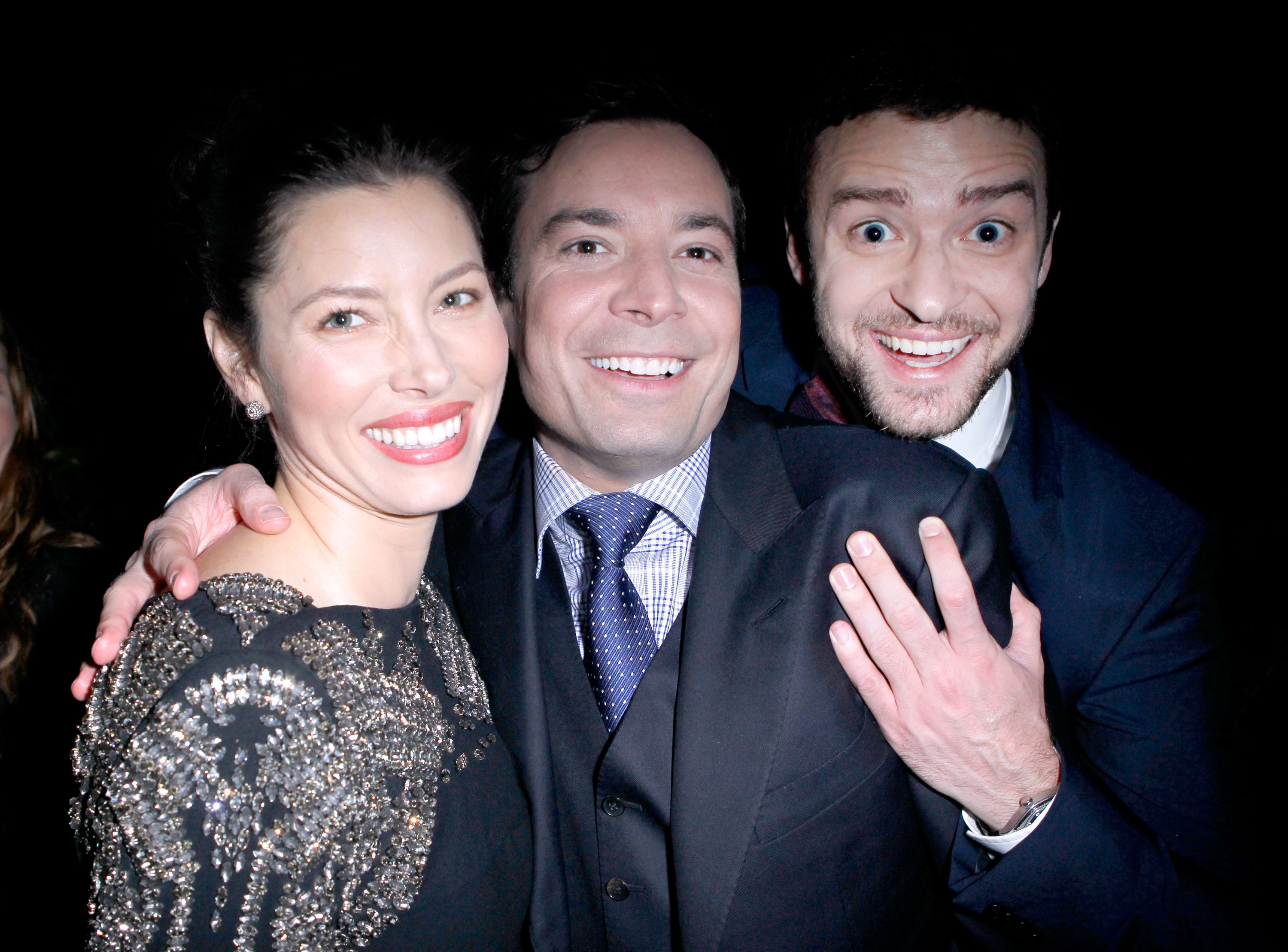 Jessica Biel and Justin Timberlake pose with comedian Jimmy Fallon at an event, smiling for the camera. Biel wears a black dress embellished with intricate silver detailing, while Timberlake sports a dark suit. | Source: Getty Images