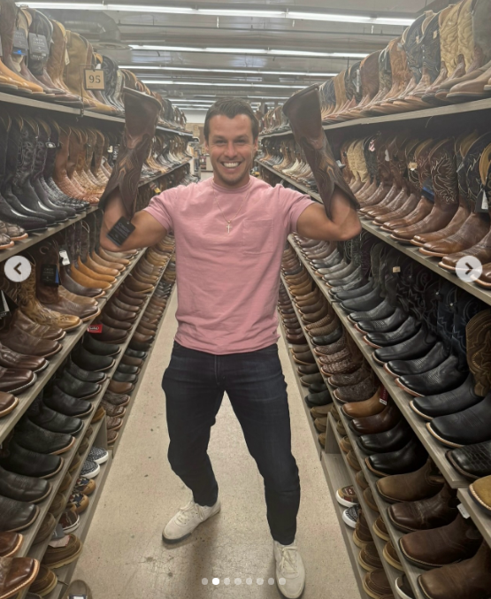 Brendan McLoughlin strikes an enthusiastic pose in the middle of a western boot aisle, holding up a pair of tall leather boots in an image shared to Miranda Lambert's Instagram on October 14, 2026. The candid snap highlighted the former New York police officer fully embracing his wife's country roots during their seven years of marriage, with fans in the comments praising his down-to-earth charm and calling the devoted husband a total catch. | Source: Instagram/mirandalambert