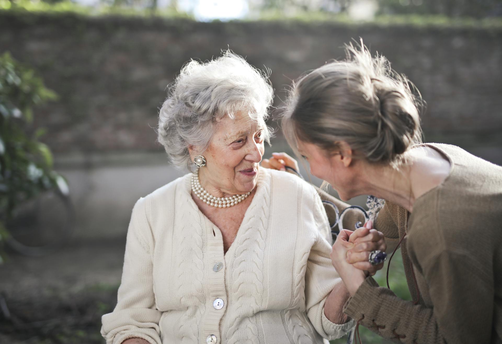 An elderly woman smiles while talking to another woman | Source: Pexels