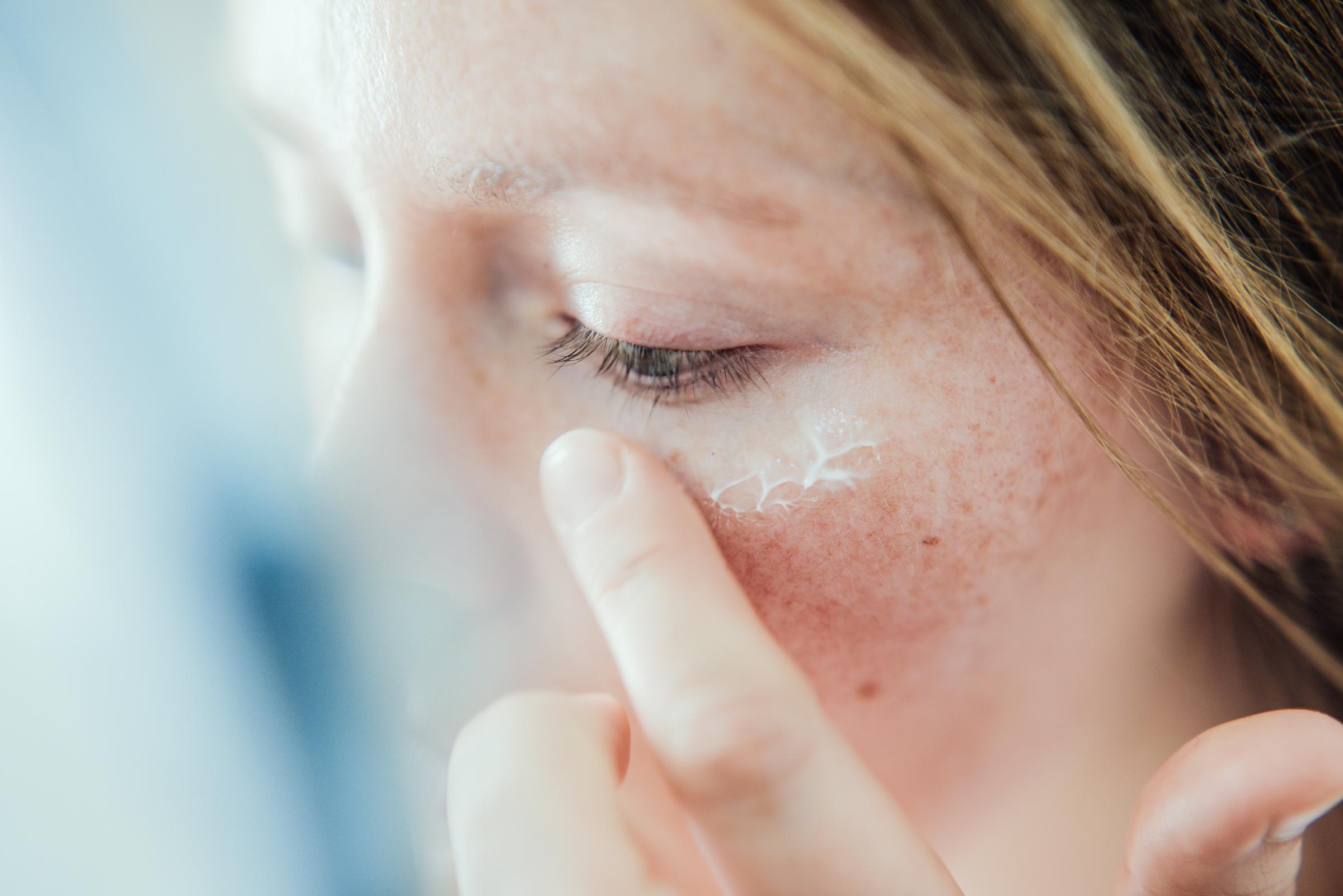 A woman applying sunscreen to her face | Source: Getty Images