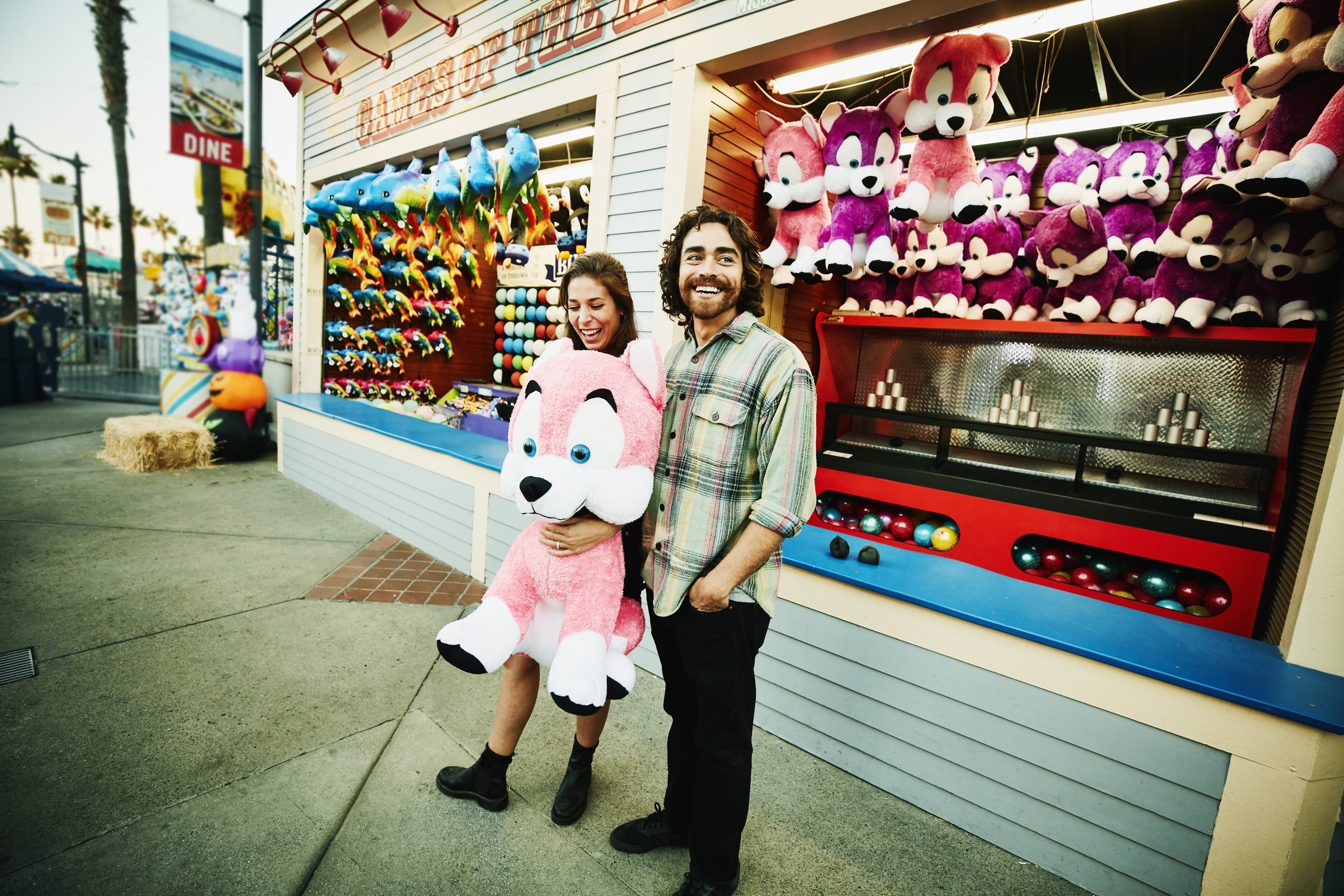 A smiling couple holding stuffed animal after winning carnival game at an amusement park | Source: Getty Images