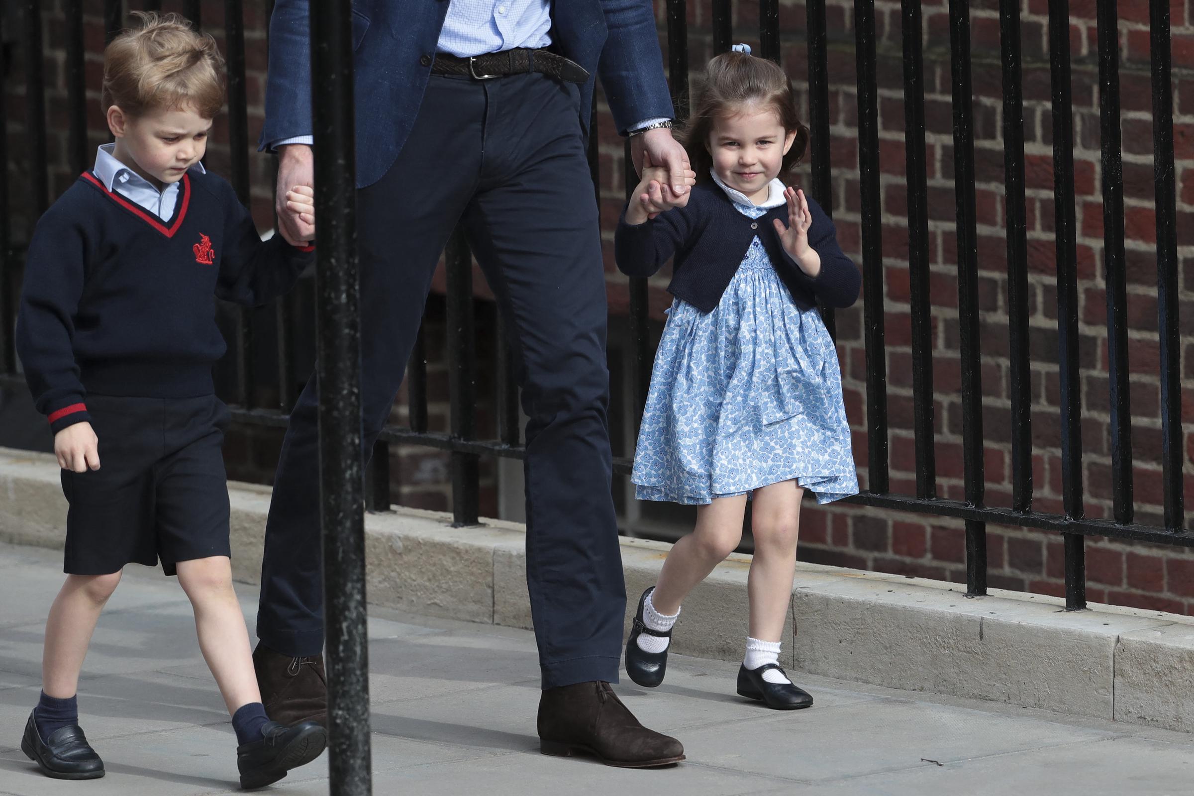 Princess Charlotte of Cambridge gives a sweet wave to onlookers outside the Lindo Wing at St Mary's Hospital on April 23, 2018, in London, England, arriving with father Prince William and brother Prince George to meet her newborn baby brother. The young royal looks charming in a blue-and-white floral smock dress paired with a navy cardigan, white socks, and Mary Jane shoes as she holds her father's hand. | Source: Getty Images