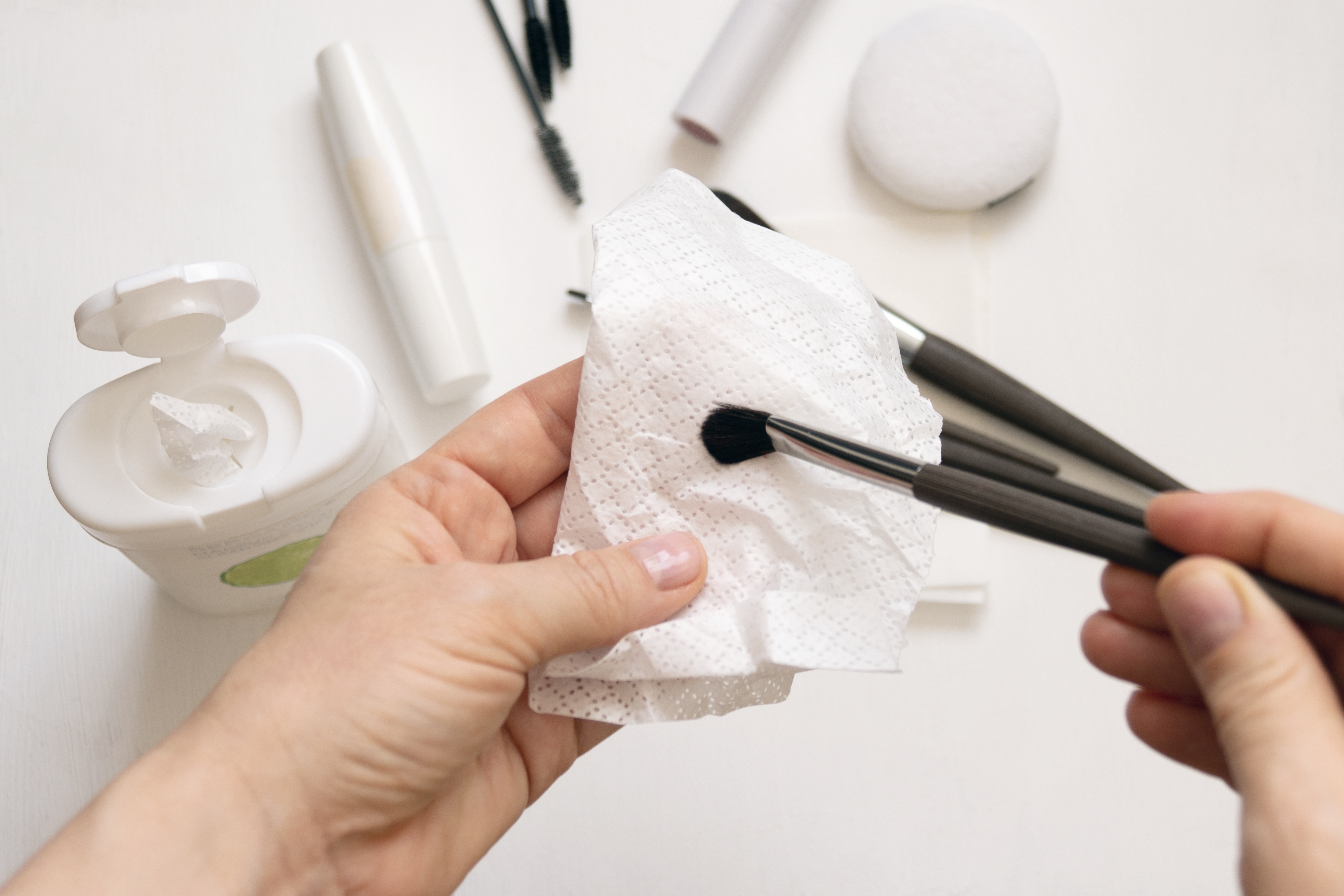 A close-up photo of a person drying a makeup brush using a paper towel | Source: Shutterstock