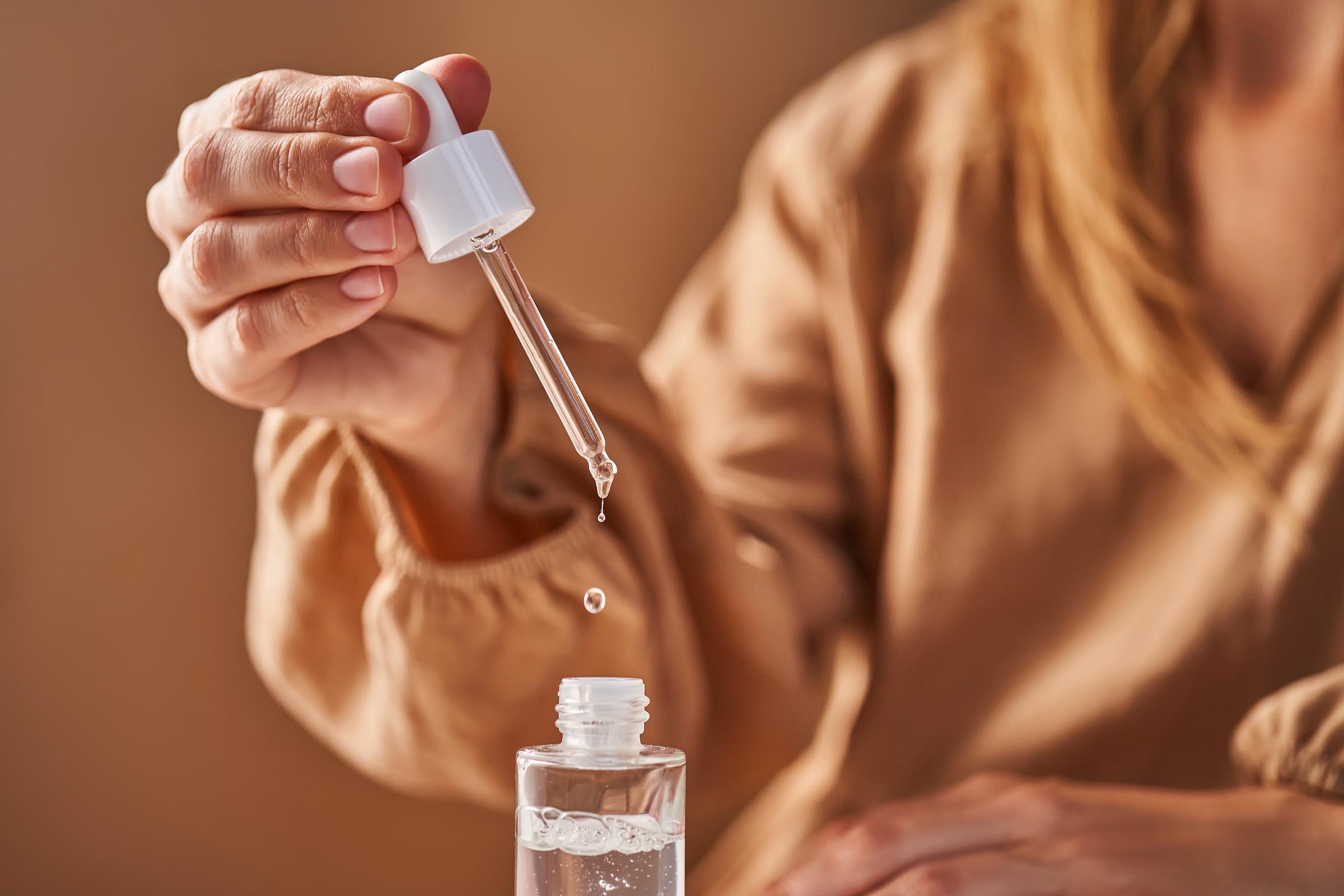 A woman holding pipette with a drop of serum in her hands | Source: Getty Images