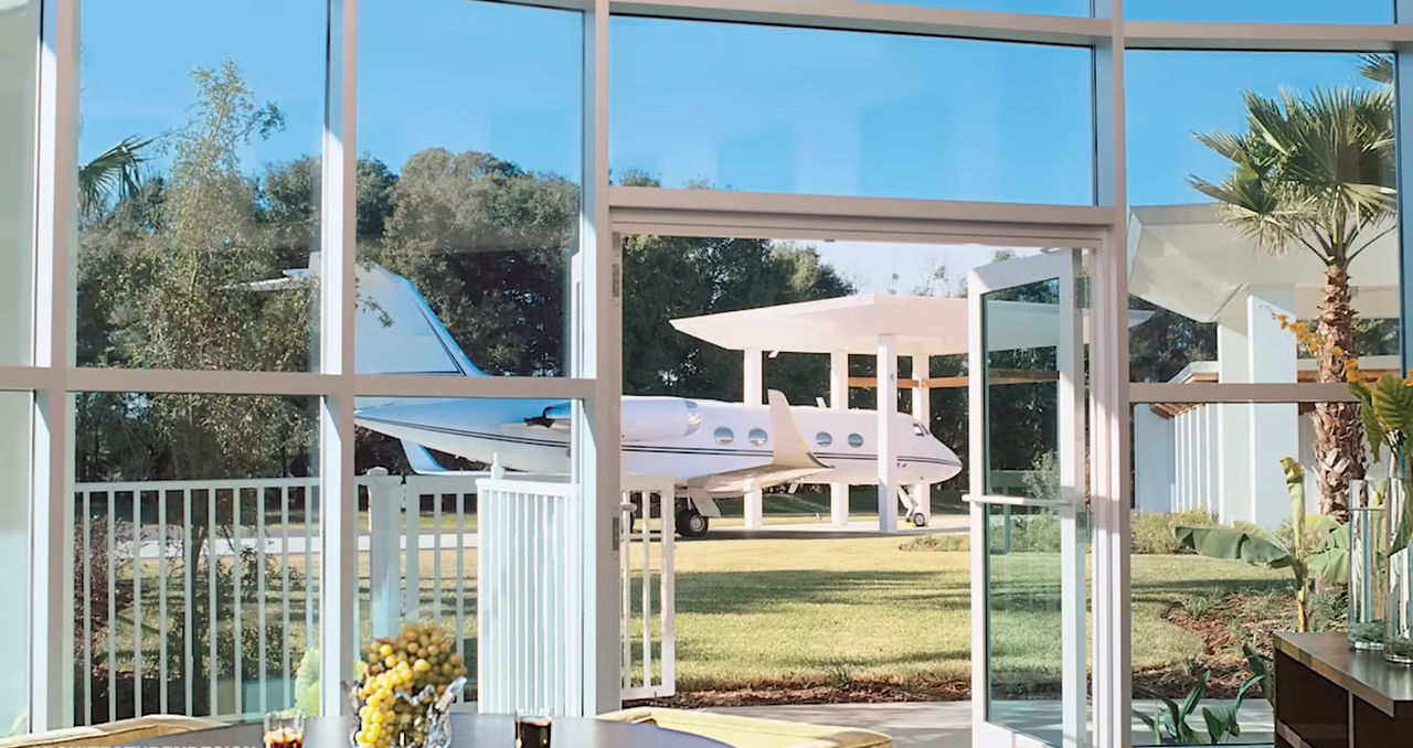 Floor-to-ceiling windows offer a striking view of a private jet parked just outside the residence. | Source: YouTube/@Therichest