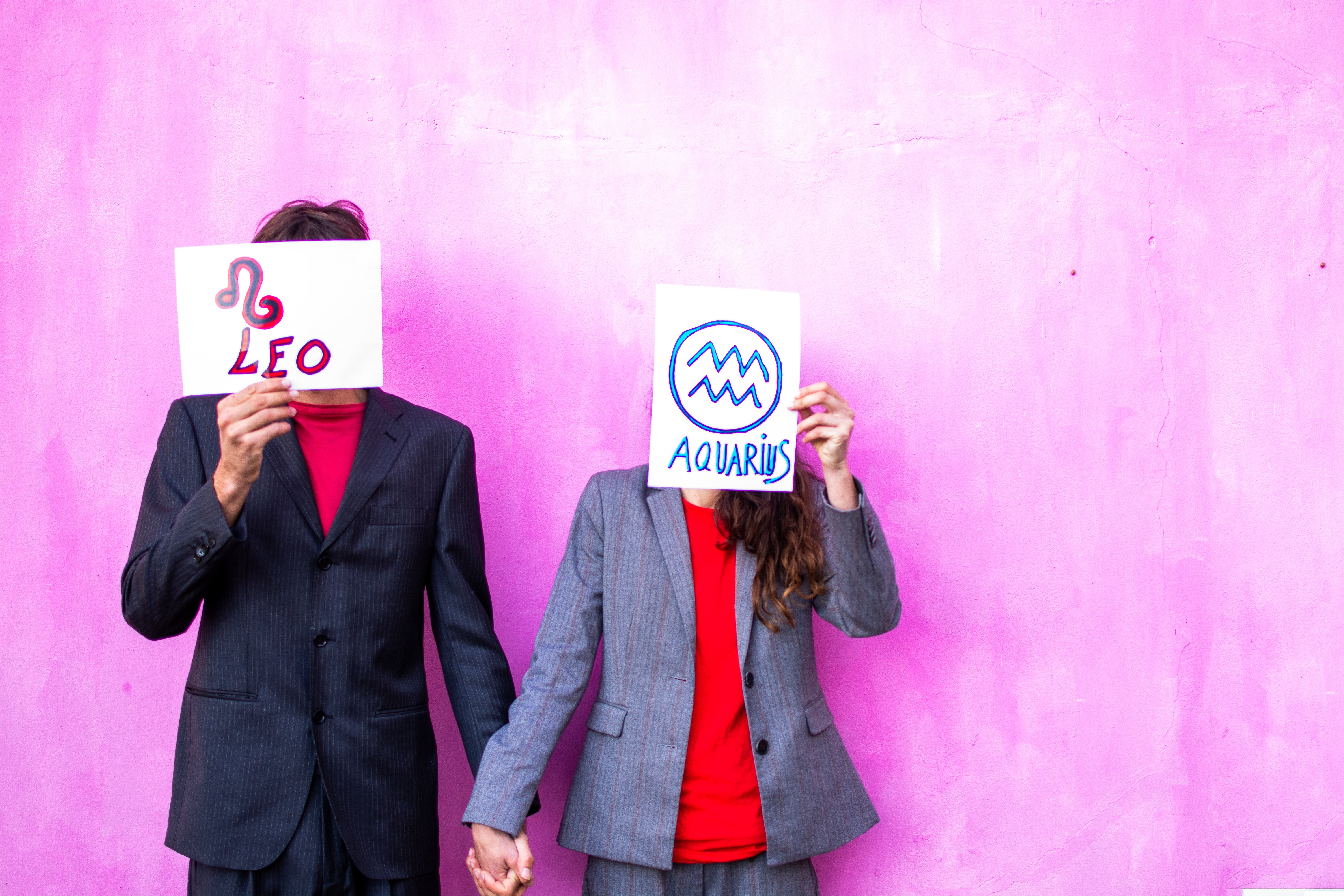 Couple holding up their star signs. | Source: Getty Images