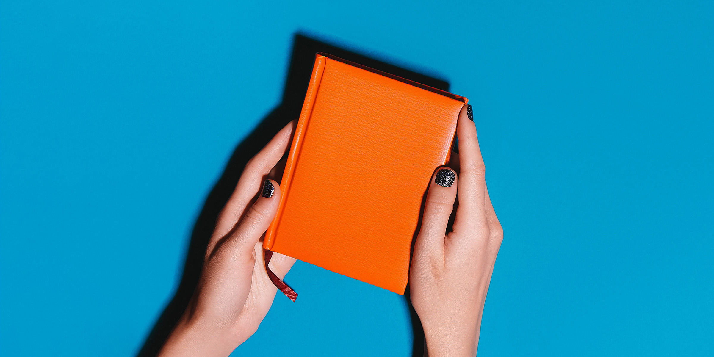 A woman's hands holding an orange journal | Source: Getty Images