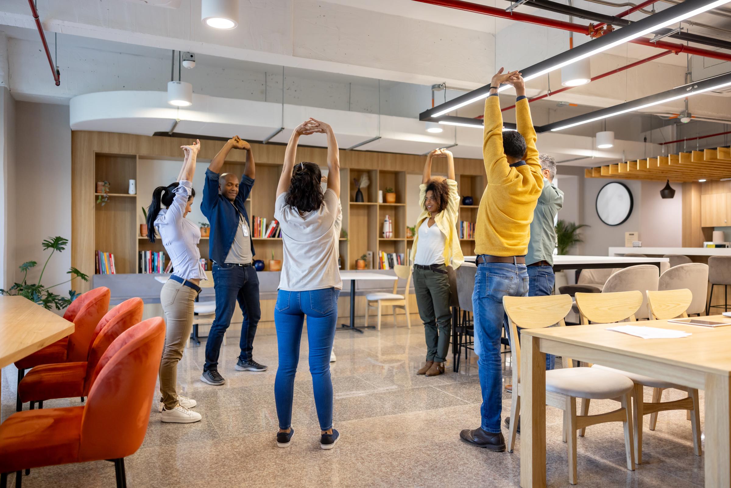 A group of people taking an active break at the office and stretching | Source: Getty Images