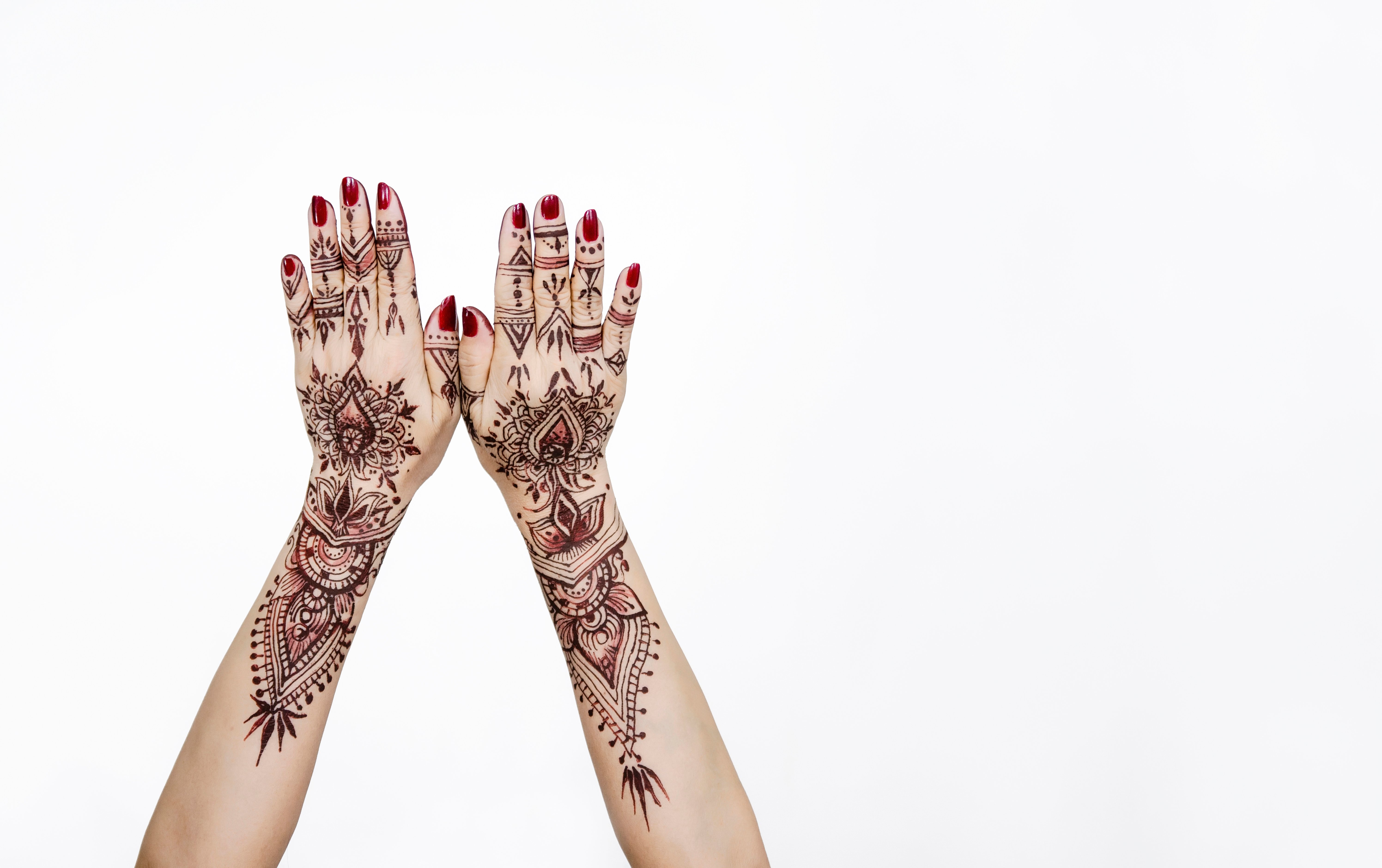 A close-up image of a woman's hands with henna tattoos against a white background. | Source: Getty Images