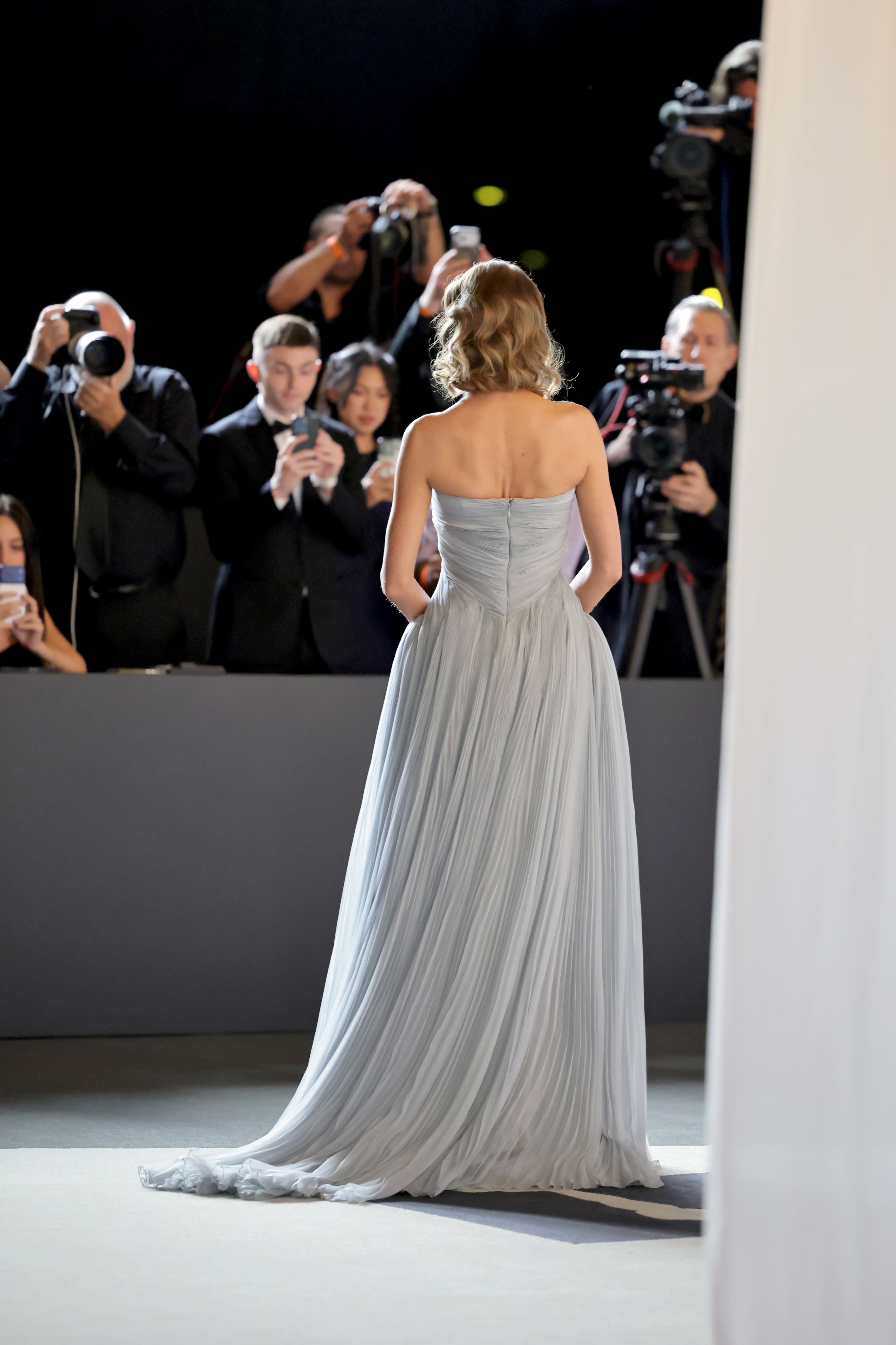 Seen from behind, Swift's softly pleated gown falls into a flowing floor-length skirt and subtle train as photographers capture her arrival.