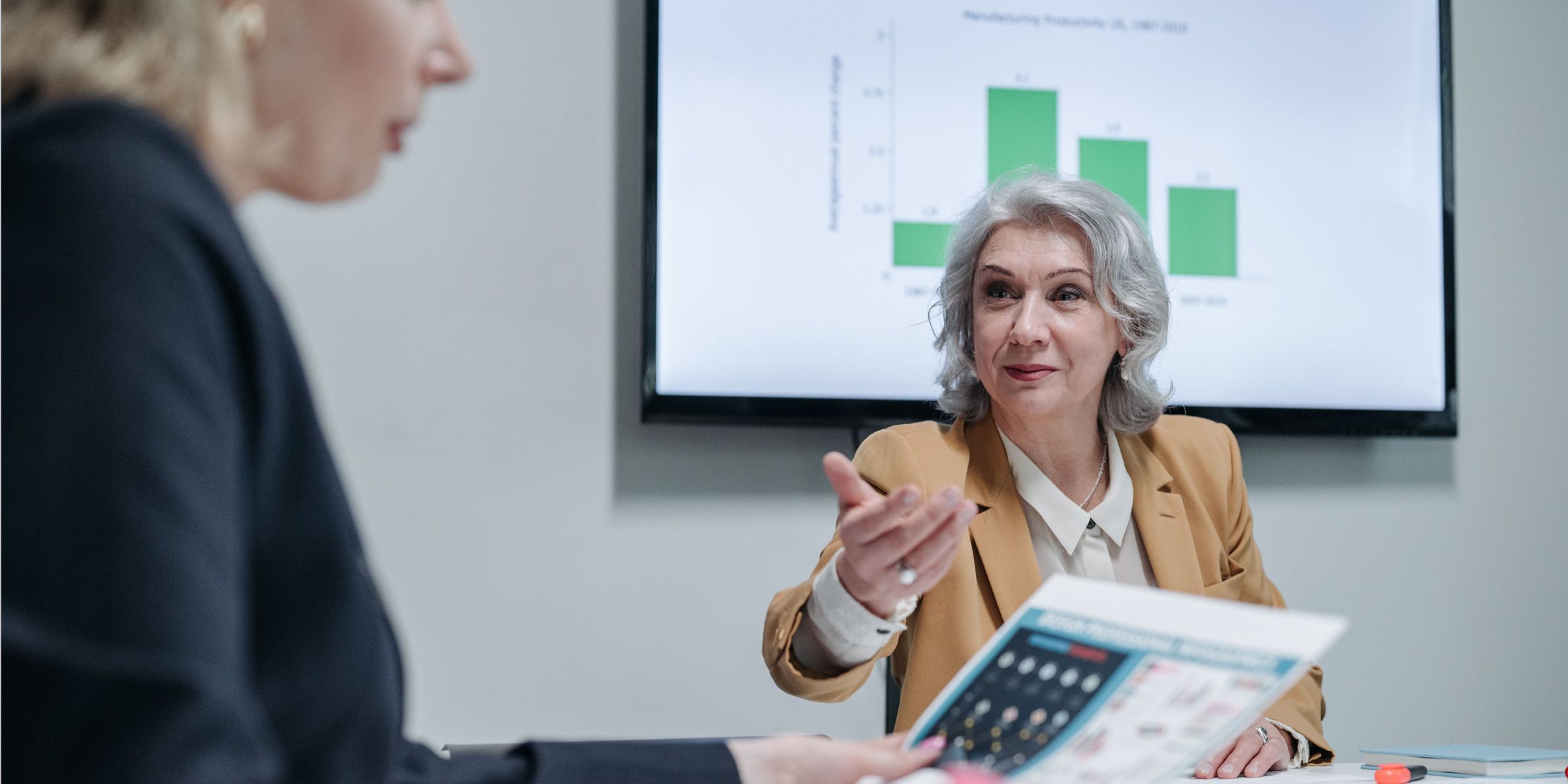 A woman signaling to another woman during a meeting | Source: Pexels