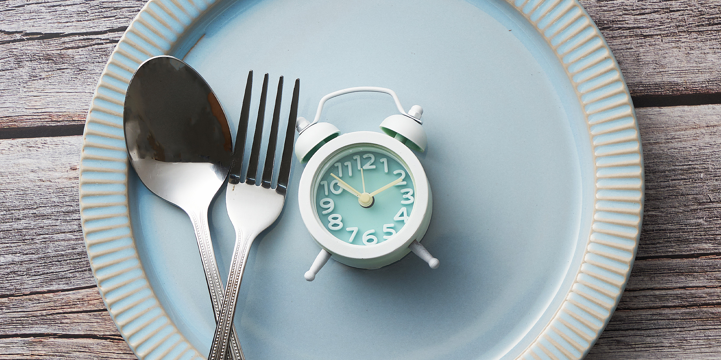 A spoon, fork, and tiny alarm clock on a plate | Source: Getty Images