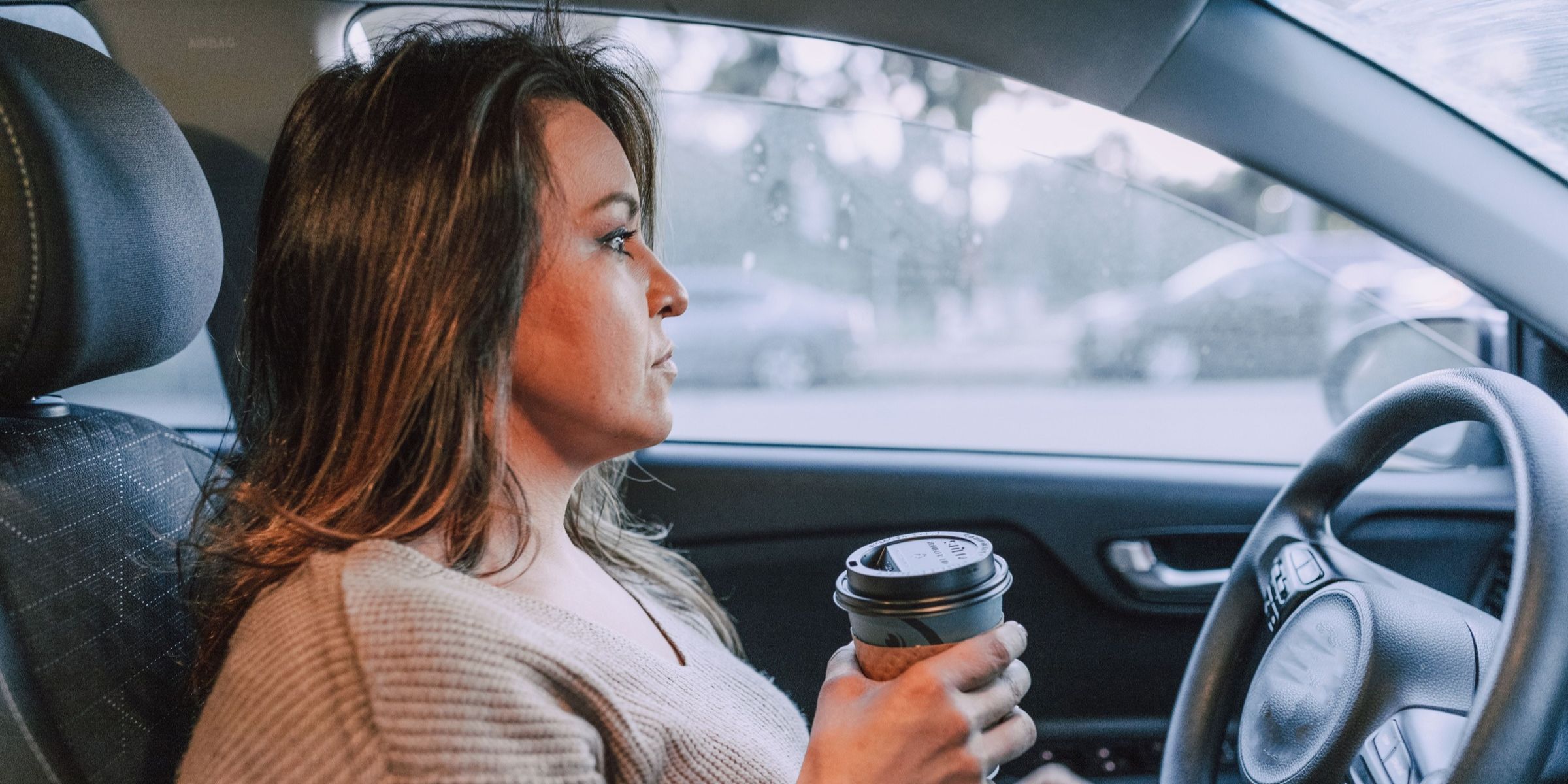 A woman driving a car and holding a coffee cup | Source: Pexels