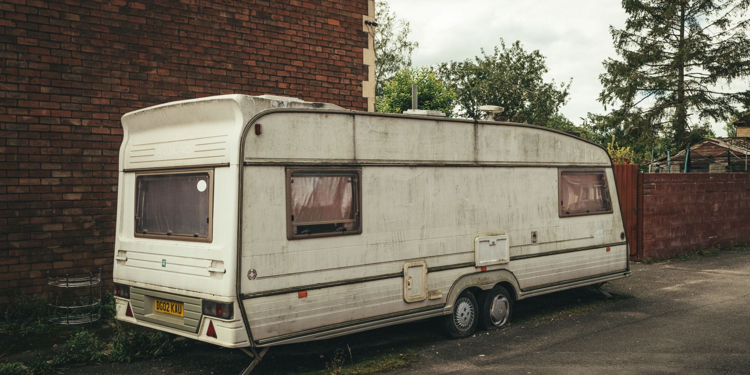 An old trailer parked next to a brick wall | Source: Pexels