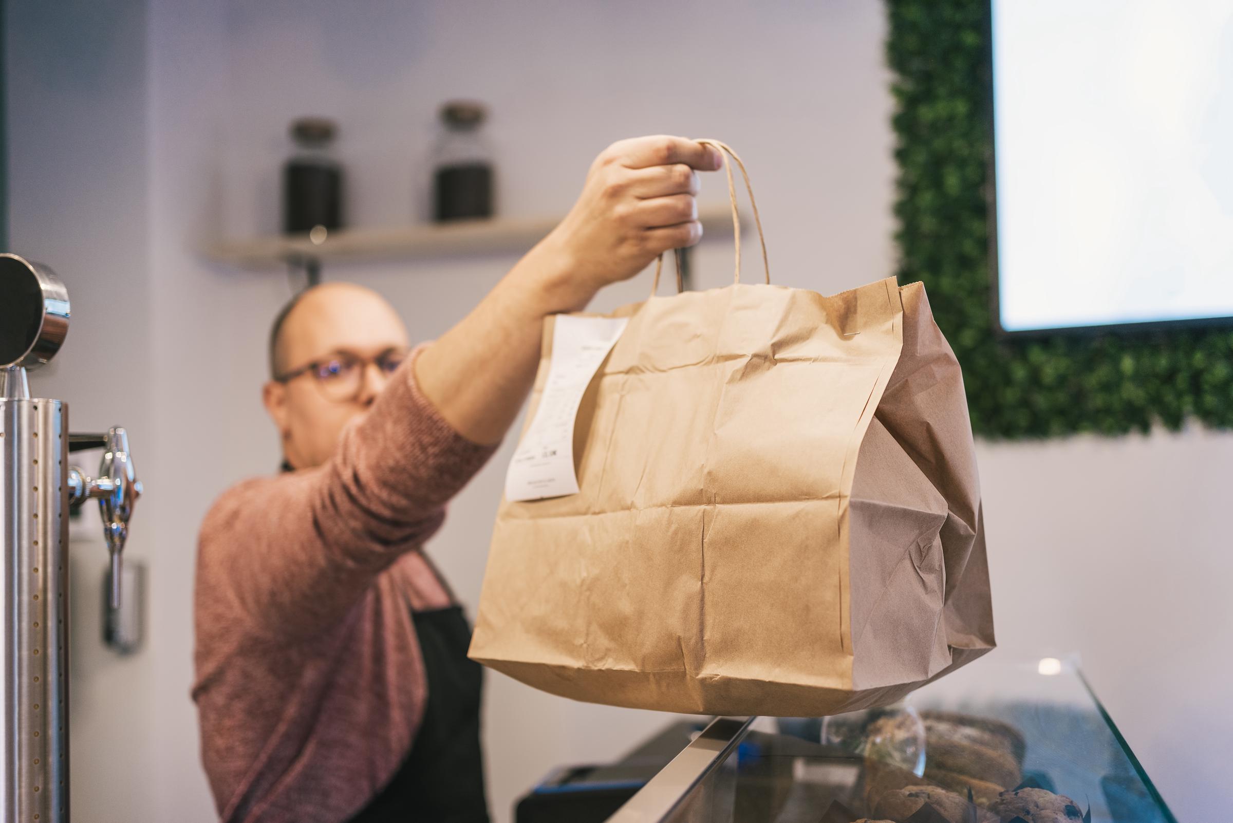 A man handing a customer their takeout order | Source: Getty Images