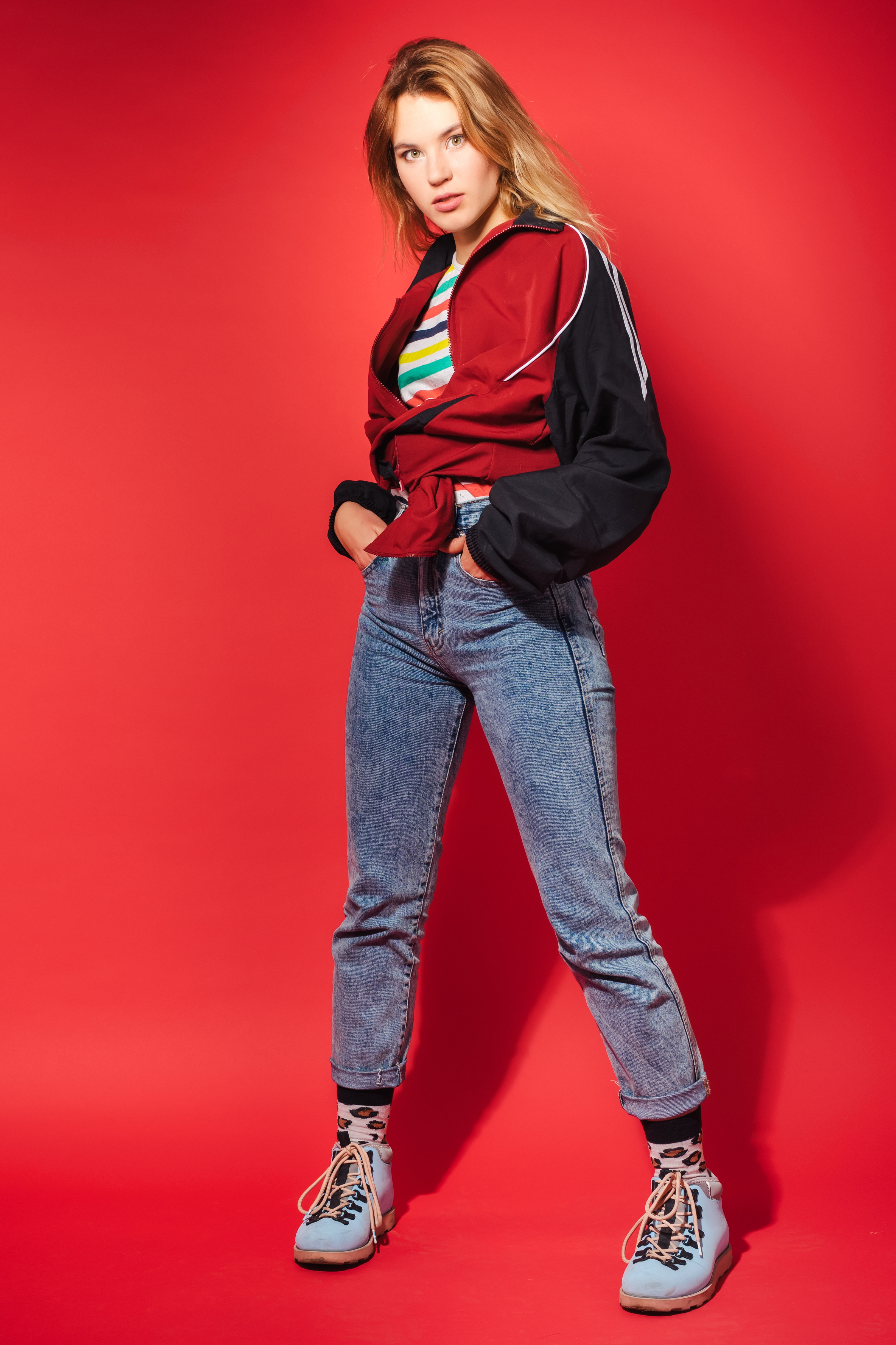 A woman styling her jeans with a red sports jacket and colorful striped tee | Source: Getty Images