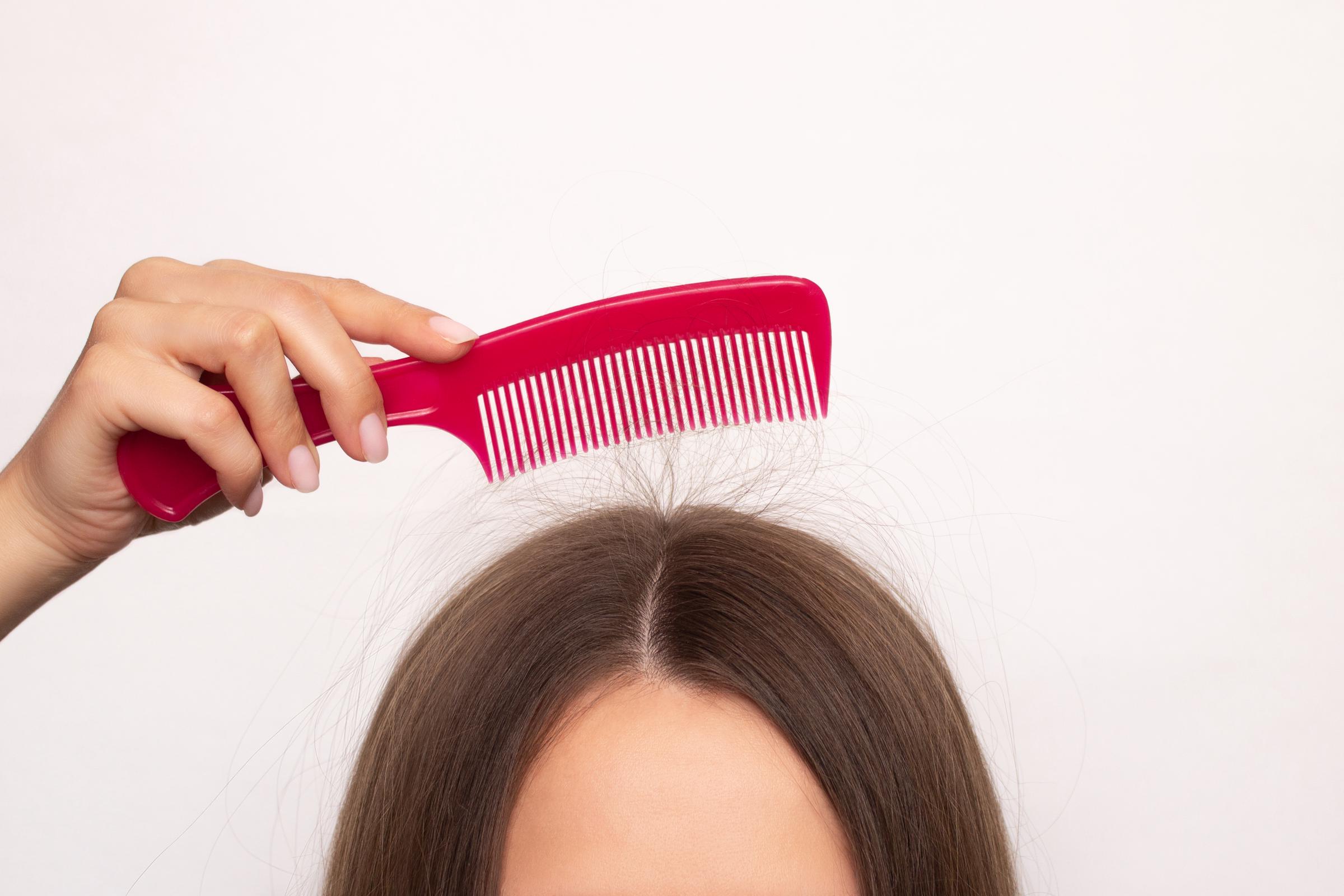 A woman combing her hair with a red comb | Source: Getty Images