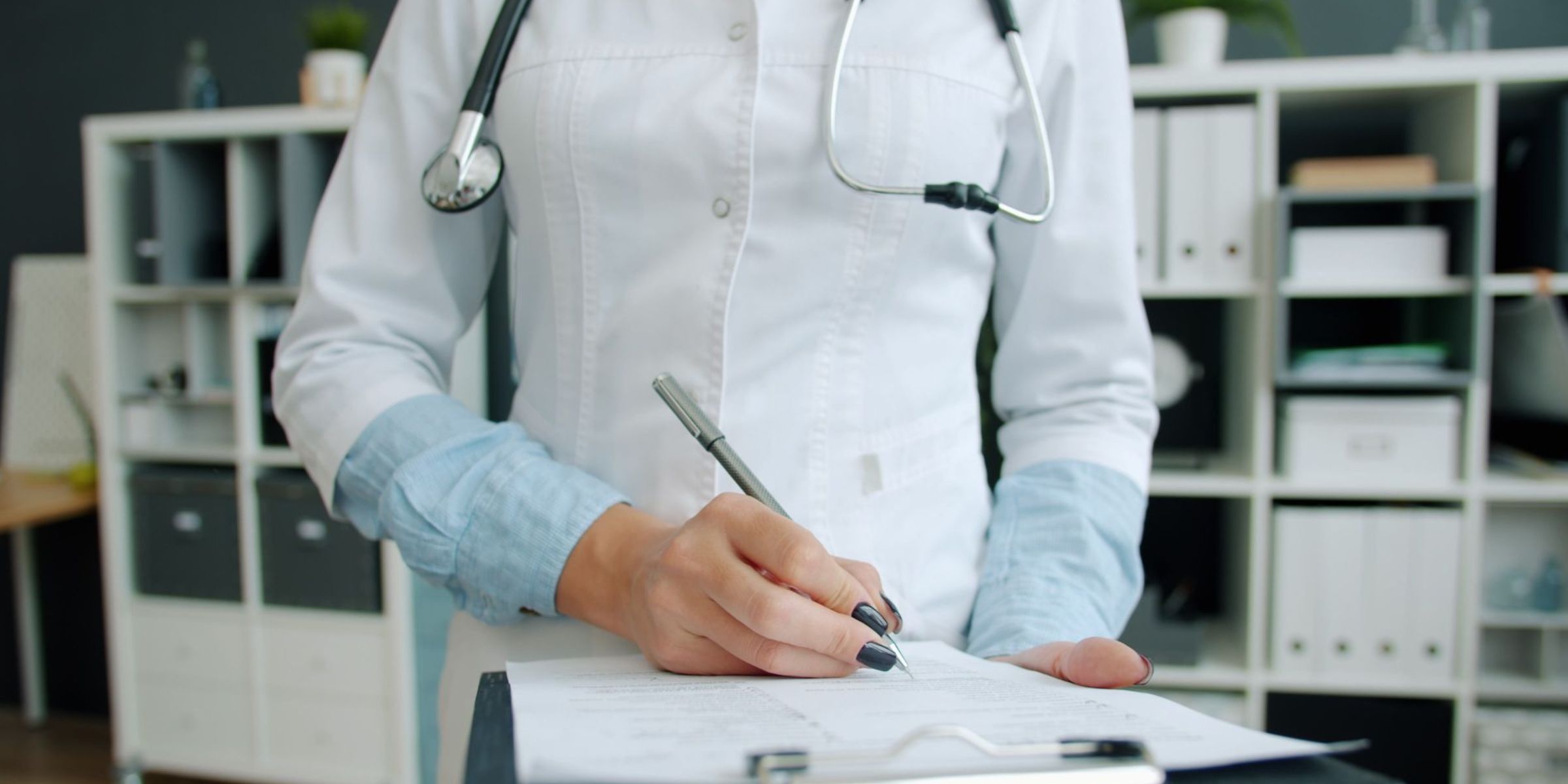 A doctor in a white coat taking notes | Source: Pexels
