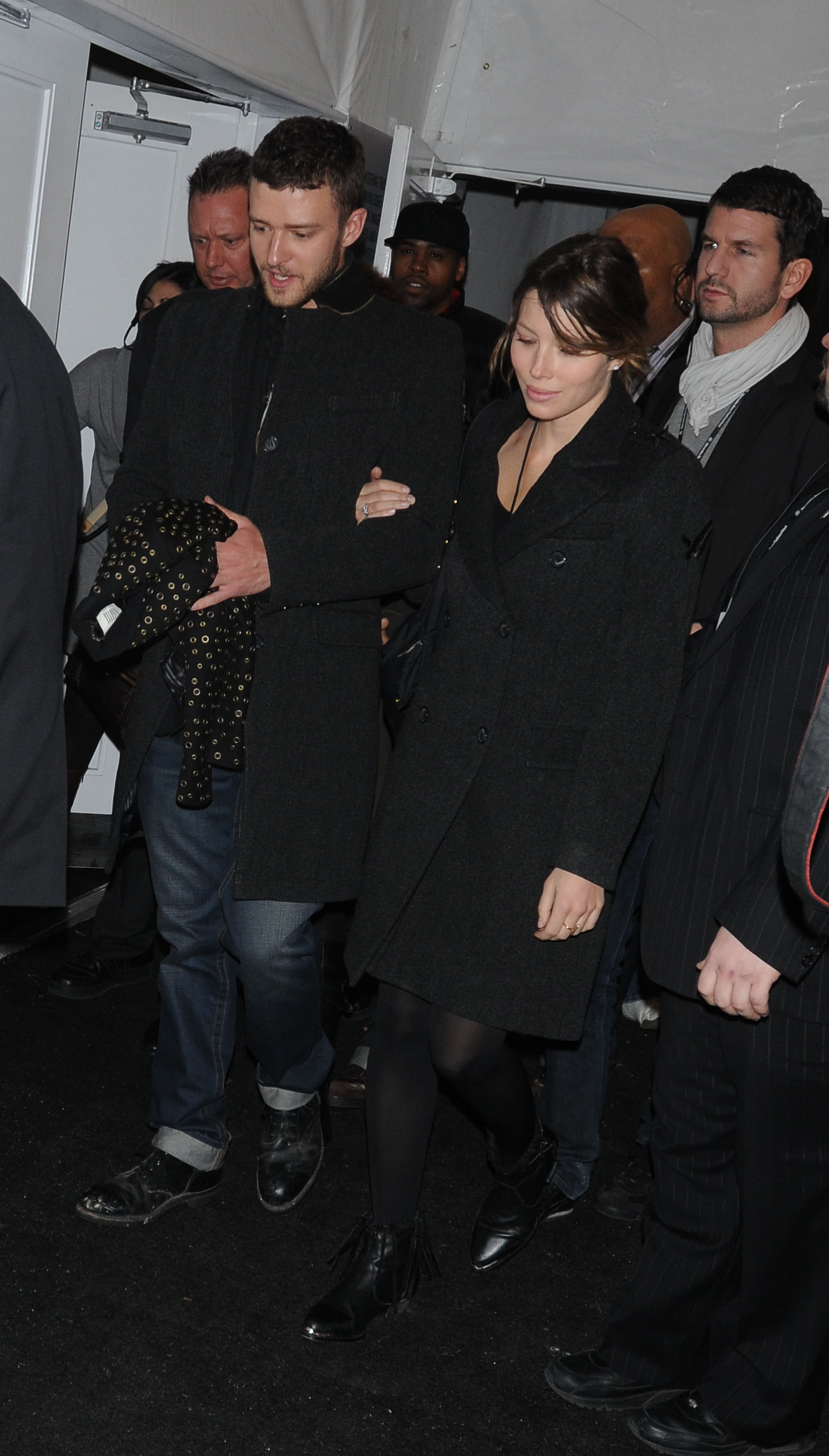 Justin Timberlake and Jessica Biel leave the William Rast fashion show hand in hand, with Biel wearing a white double-breasted coat over black trousers and Timberlake dressed in a dark suit and tie. | Source: Getty Images