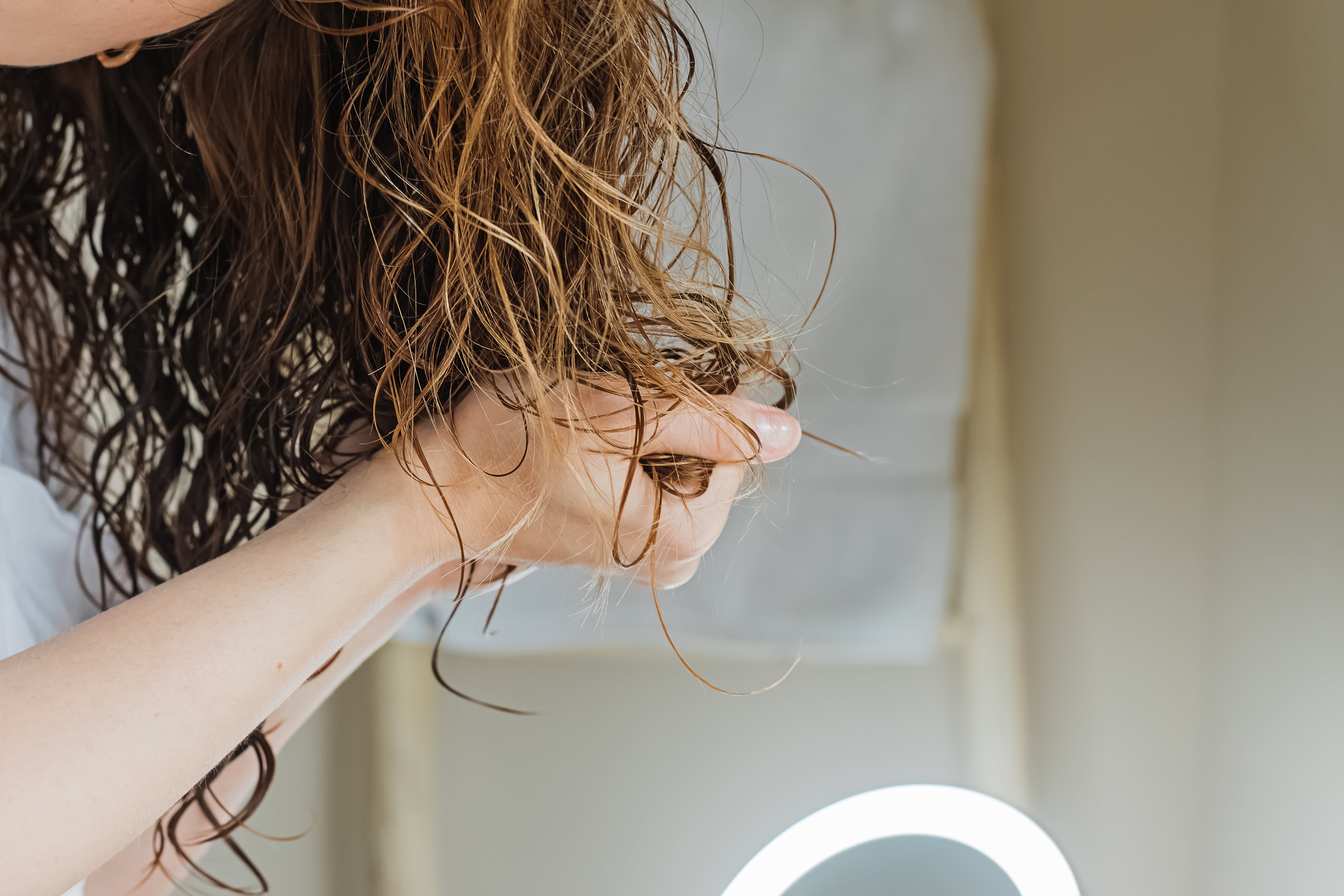 A woman scrunching her hair to define the form of her curls | Source: Shutterstock