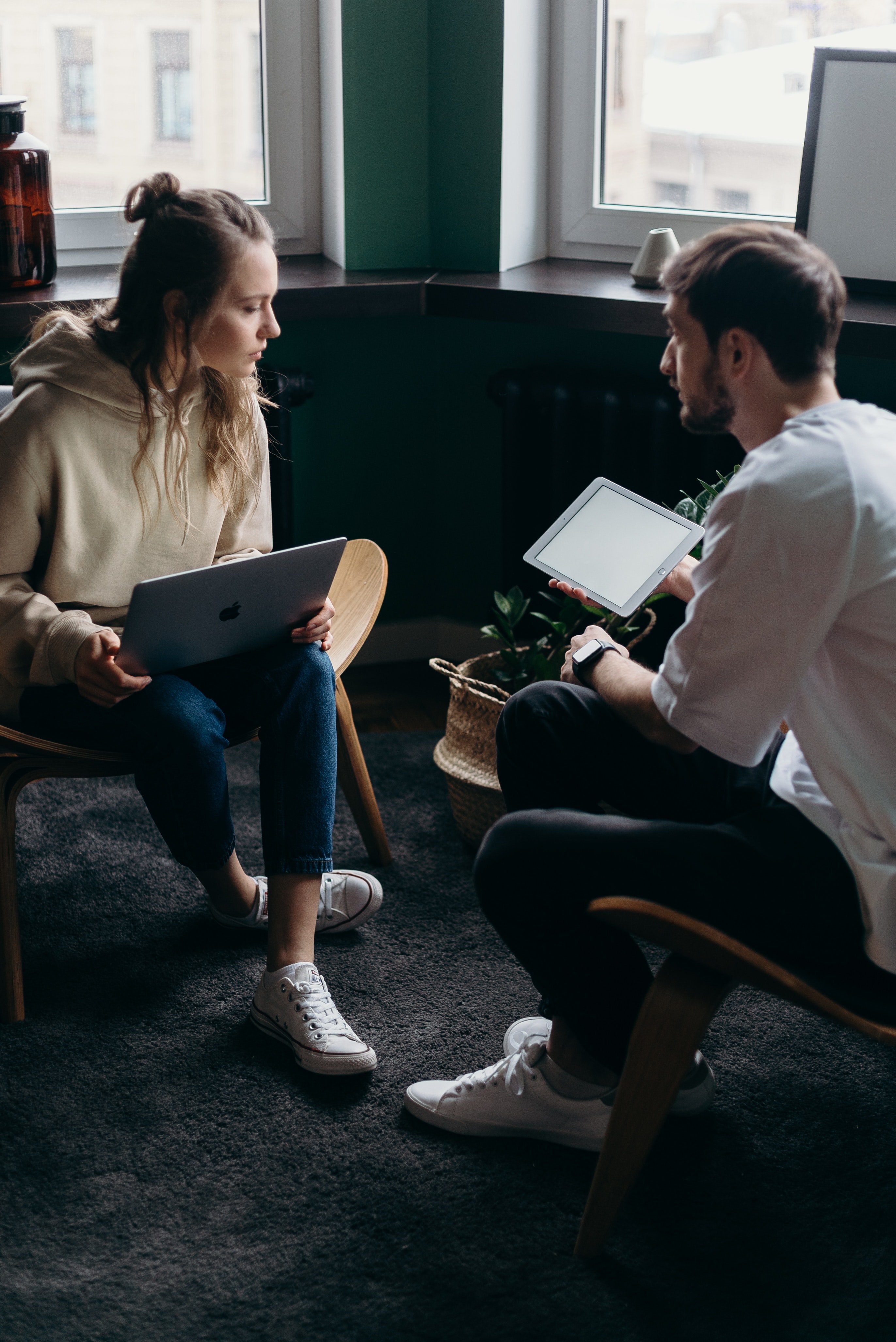 A photo of a couple talking while holding a laptop and an iPad | Source: Pexels 