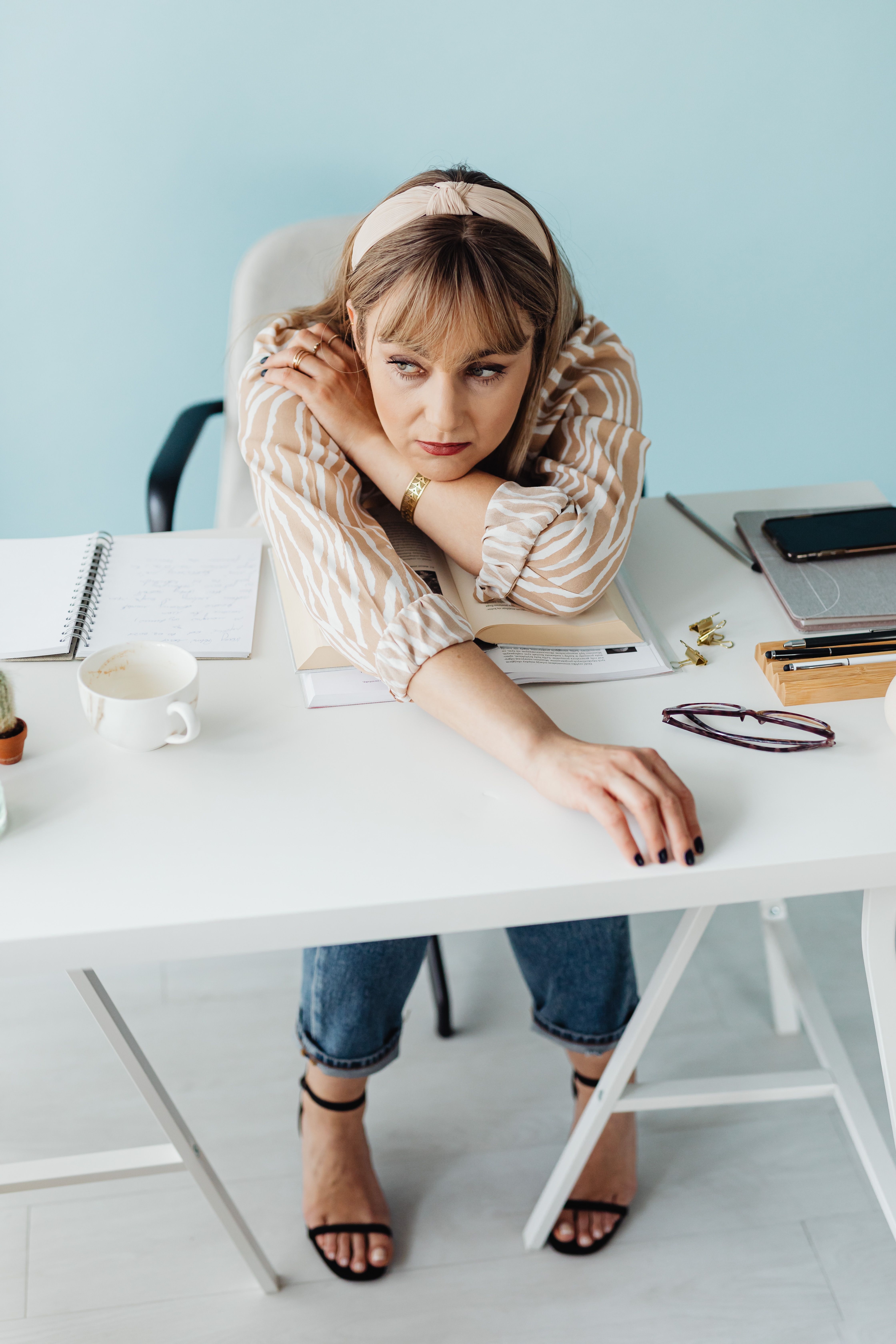 Woman leaning on an office desk, contemplating | Source: Pexels