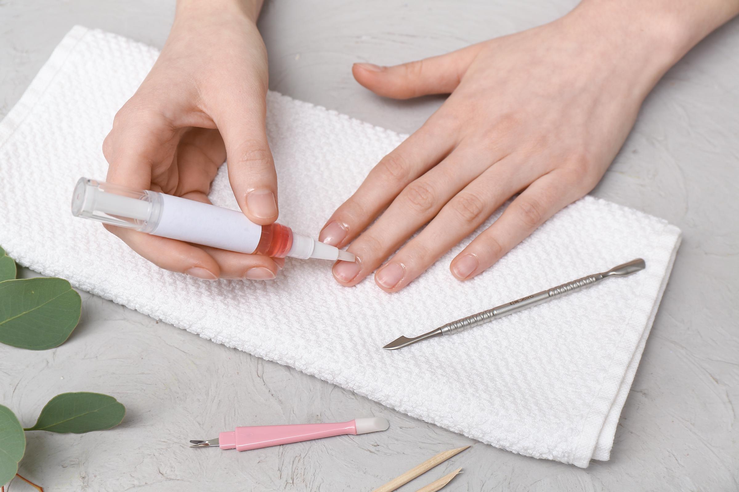 Female hands applying cuticle oil onto fingernails | Source: Shutterstock