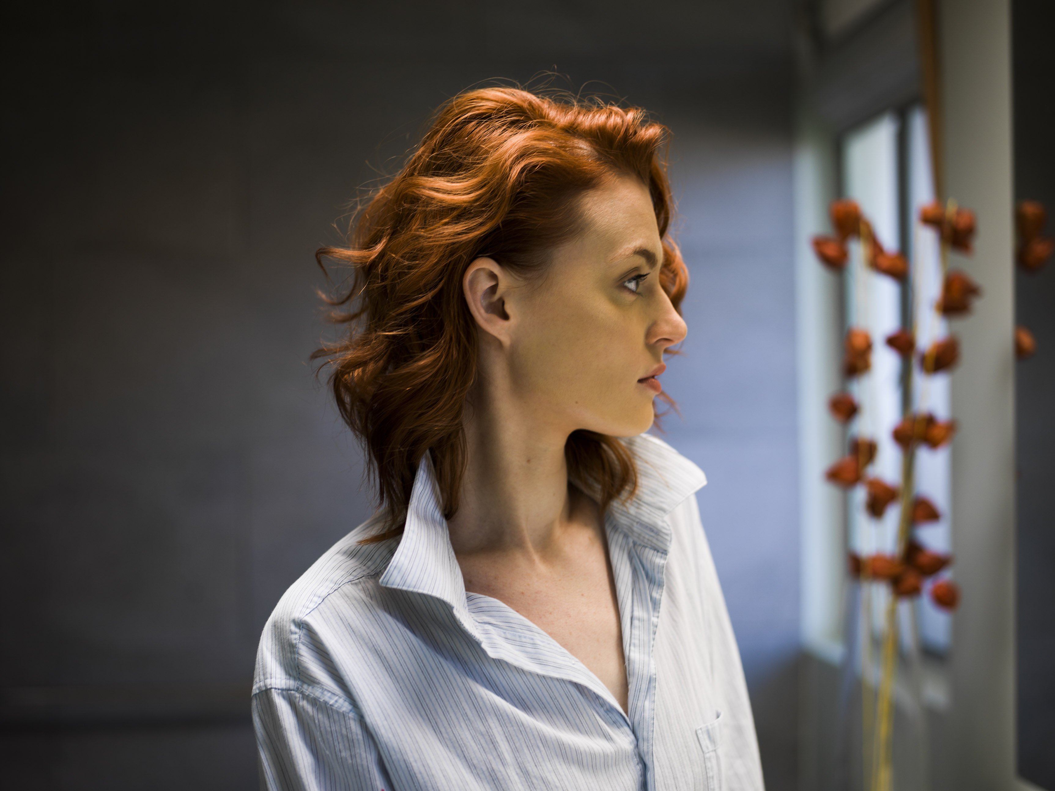 A profile portrait of redheaded woman dressed in a man's shirt | Source: Getty Images 