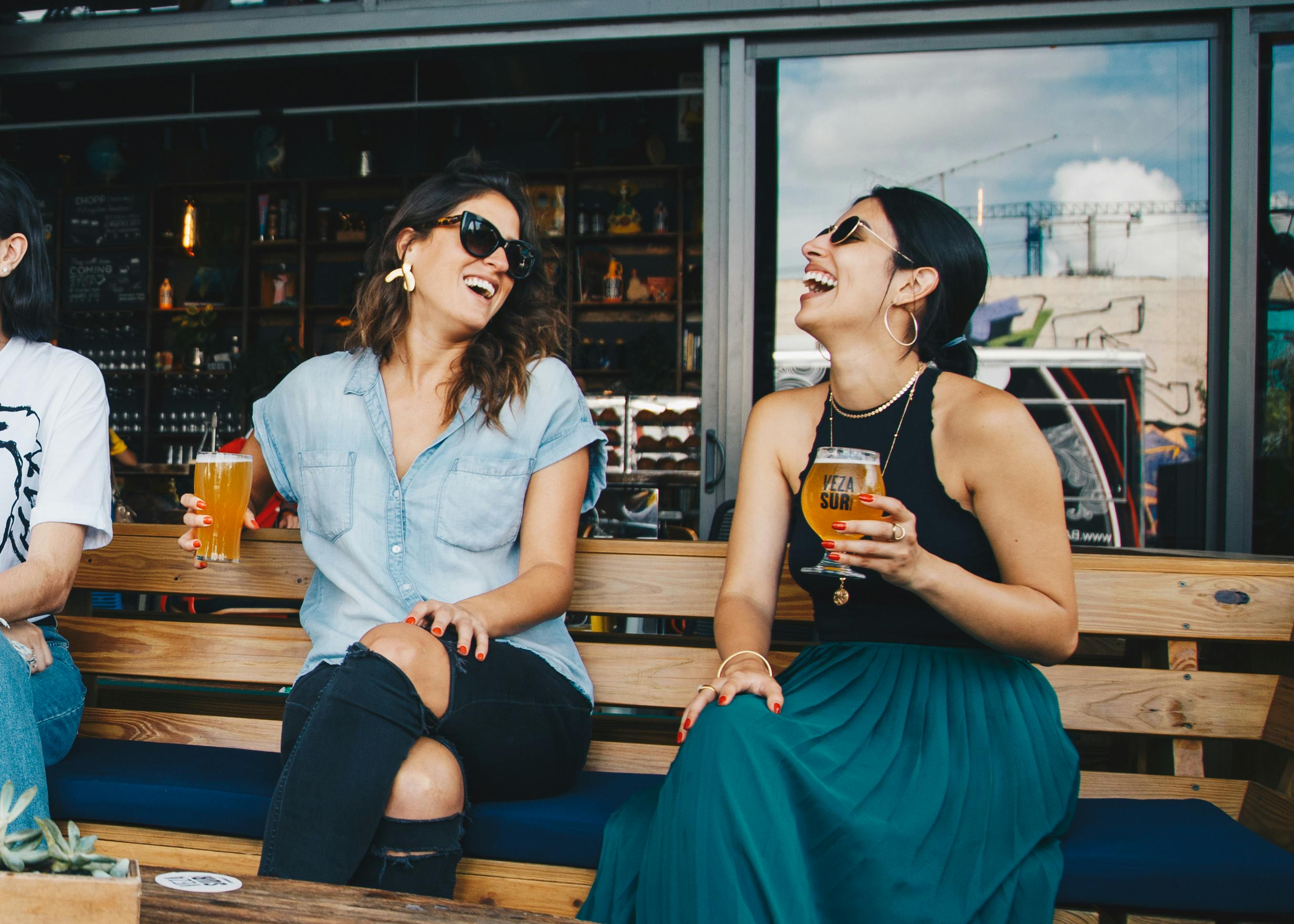 Women sitting on a wooden bench enjoying a drink | Source: Pexels