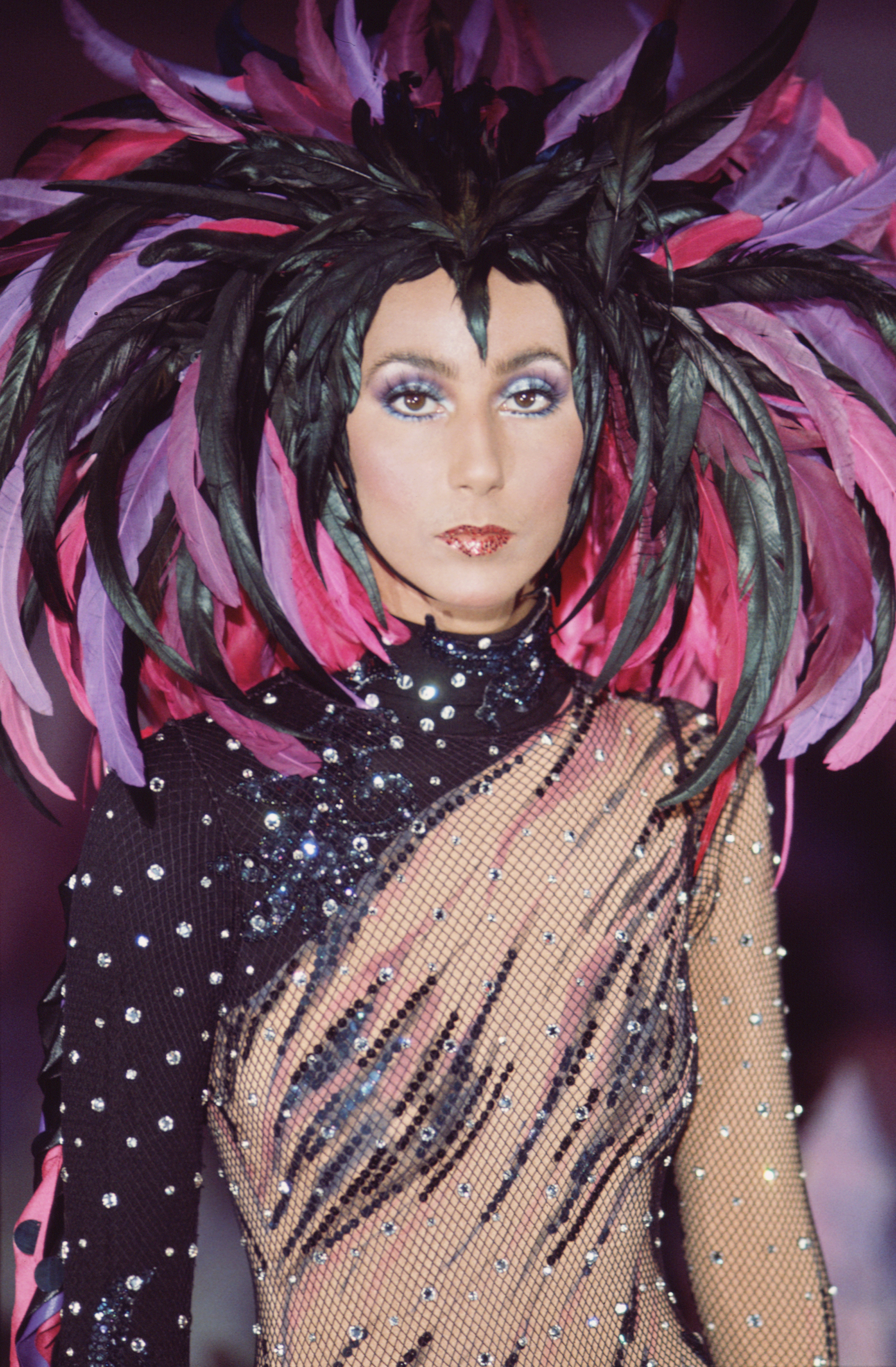 Cher in a semi-transparent outfit with a feathered headdress designed by Bob Mackie for the television variety show, "The Sonny and Cher Comedy Hour" in 1972 | Source: Getty Images