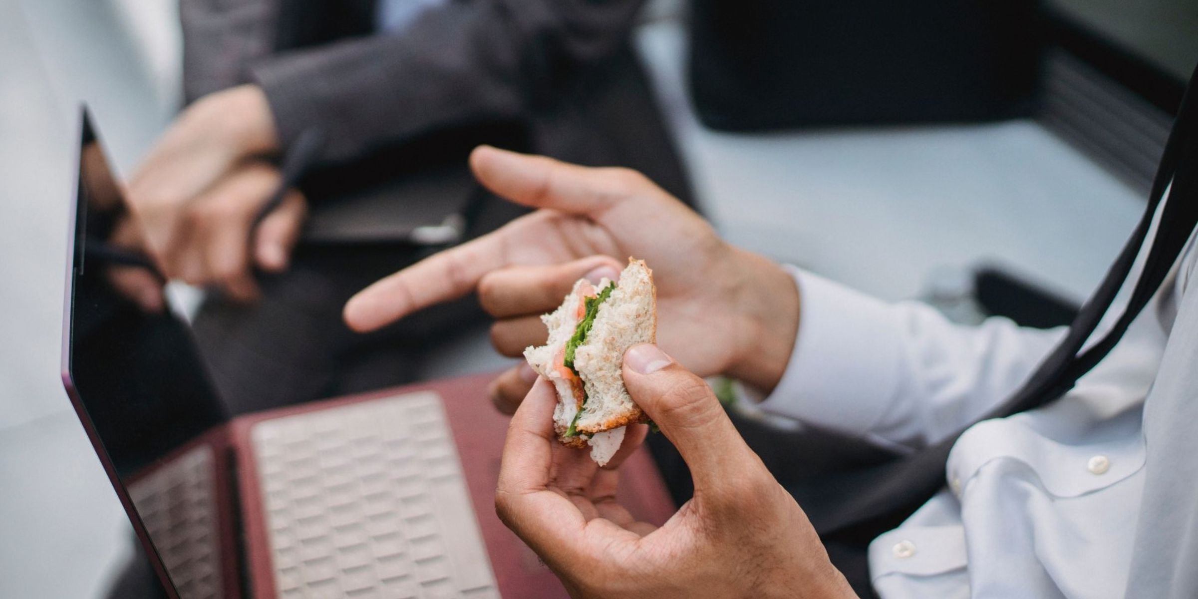 Man eating a sandwich while working on a laptop | Source: Pexels