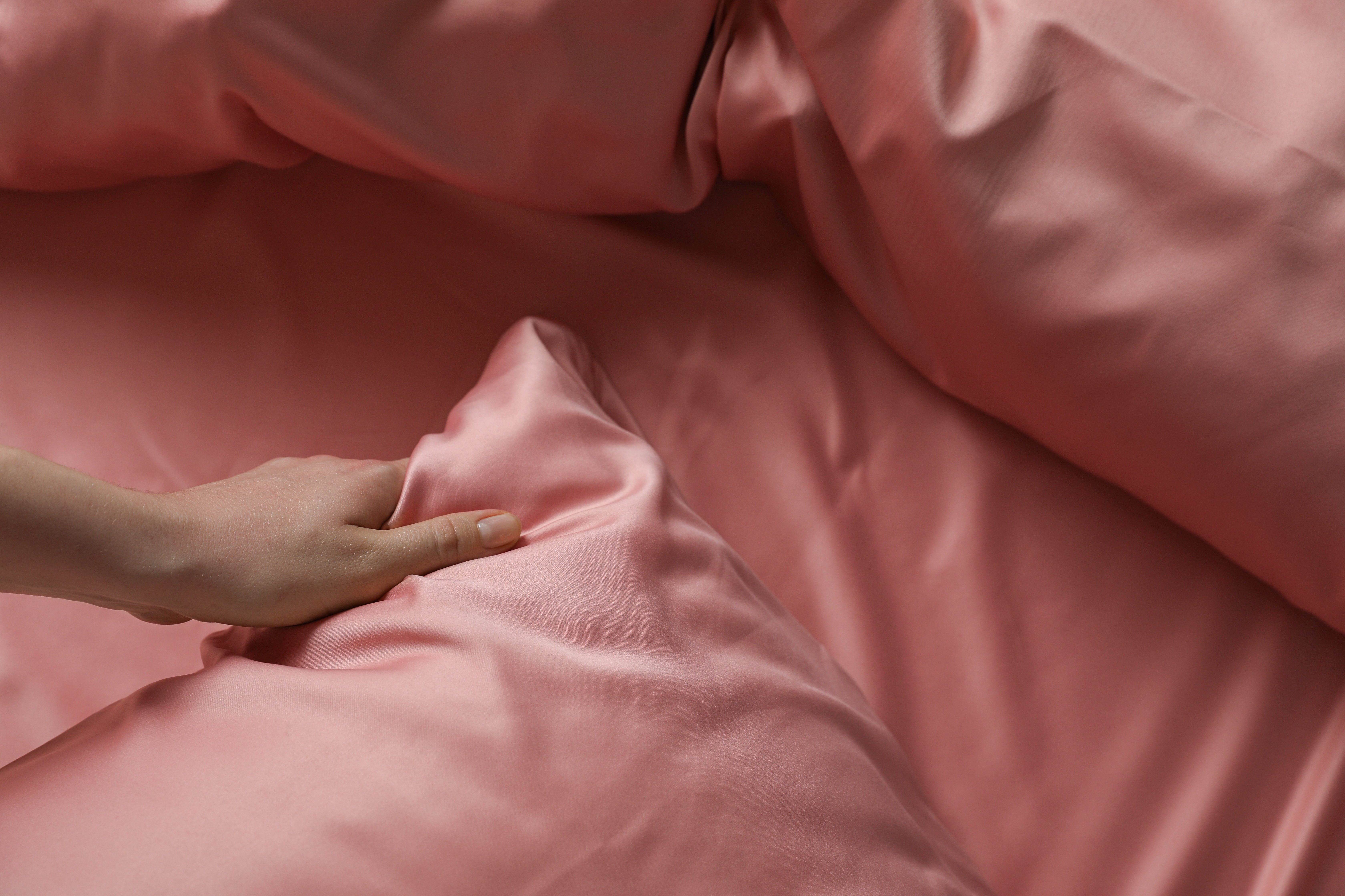 Woman with satin pillowcases and bed sheets. | Source: Getty Images