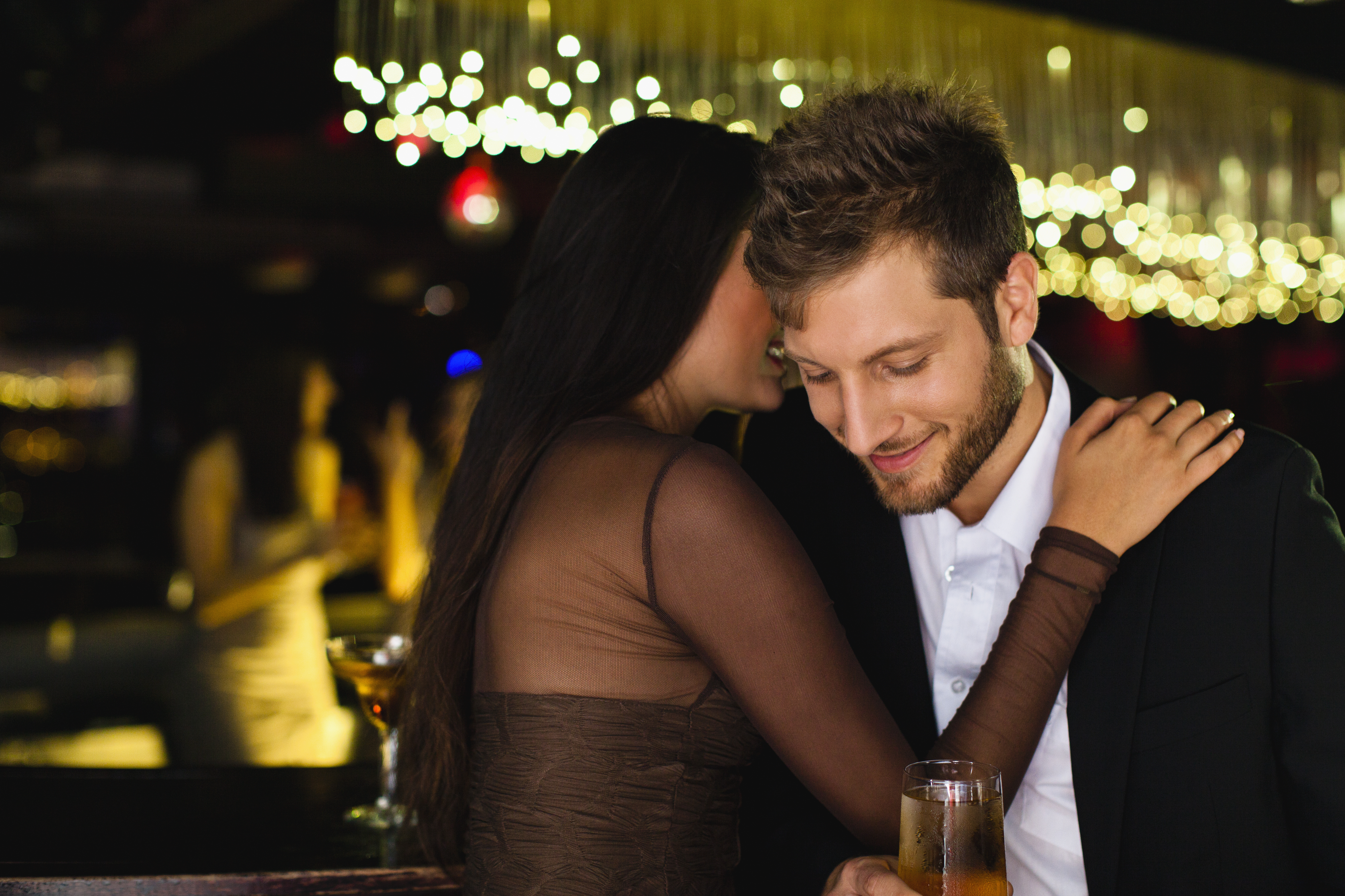 A woman whispering in a man's ear. | Source: Getty Images