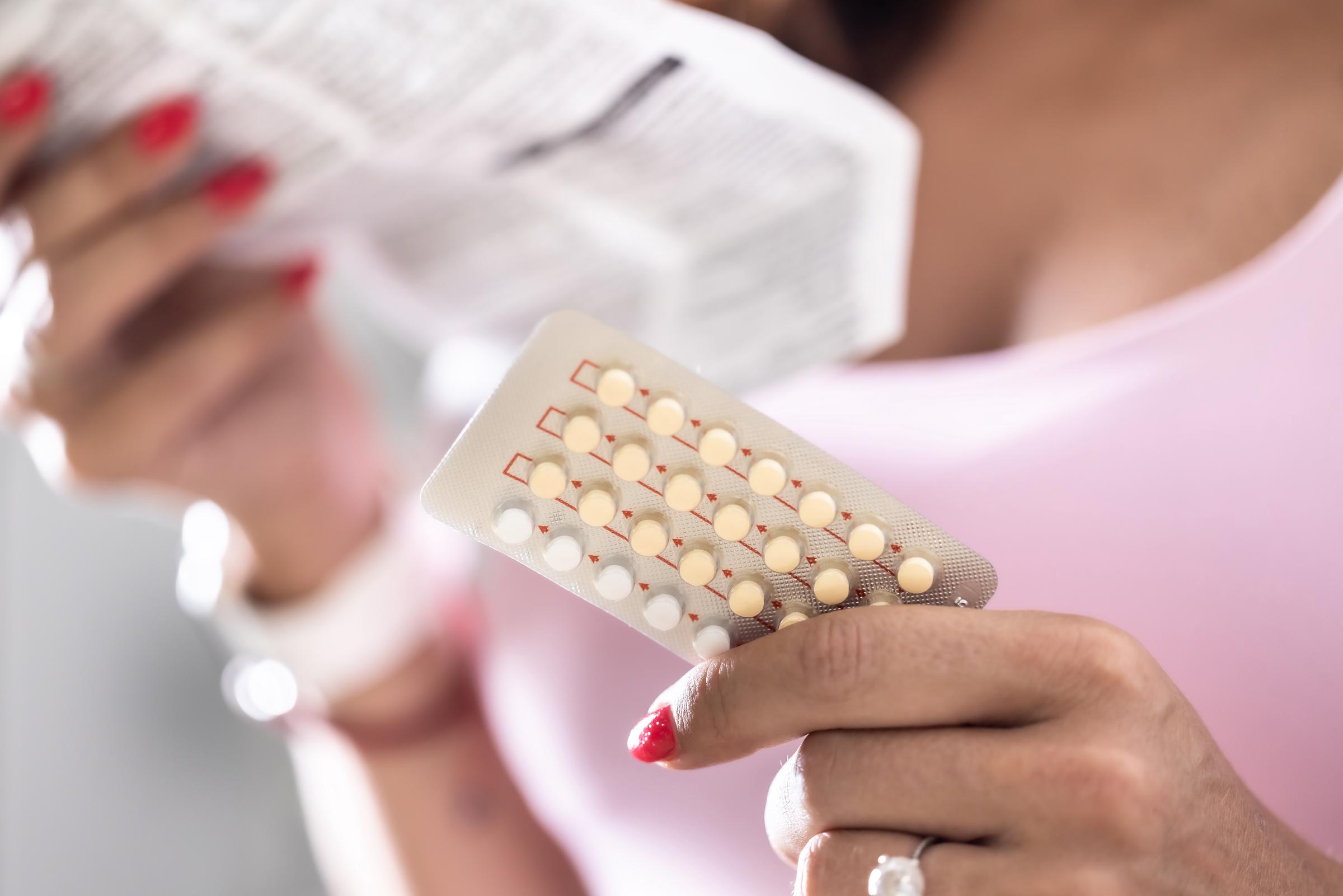 A woman reading the package insert of a contraceptive pill | Source: Getty Images