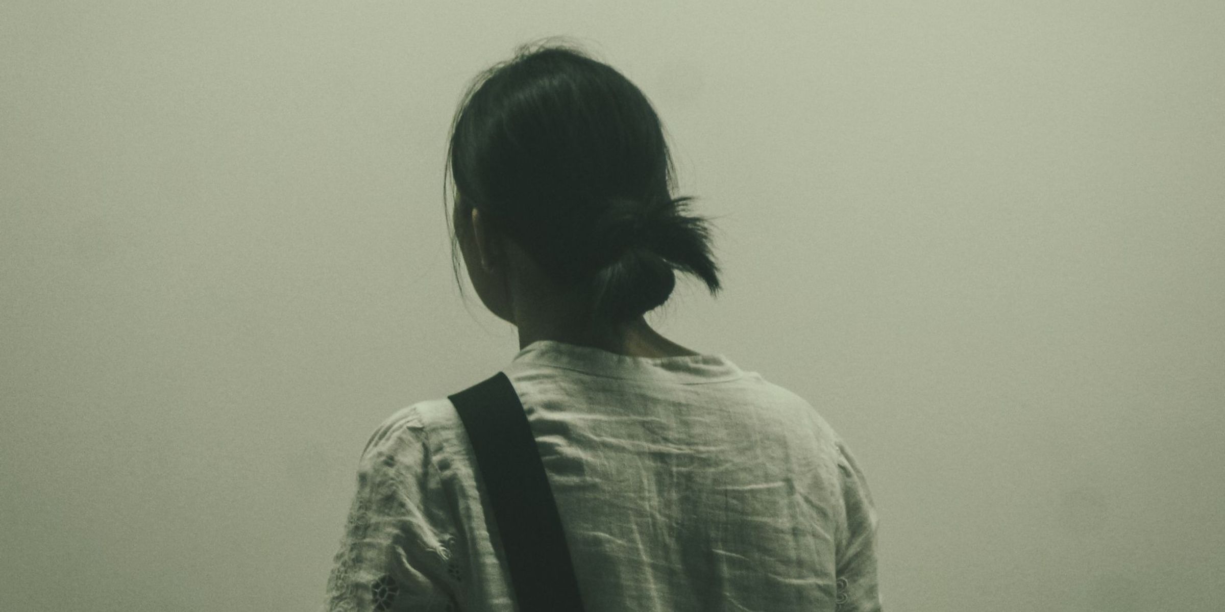 Woman with dark hair seen from behind against a plain wall | Source: Pexels
