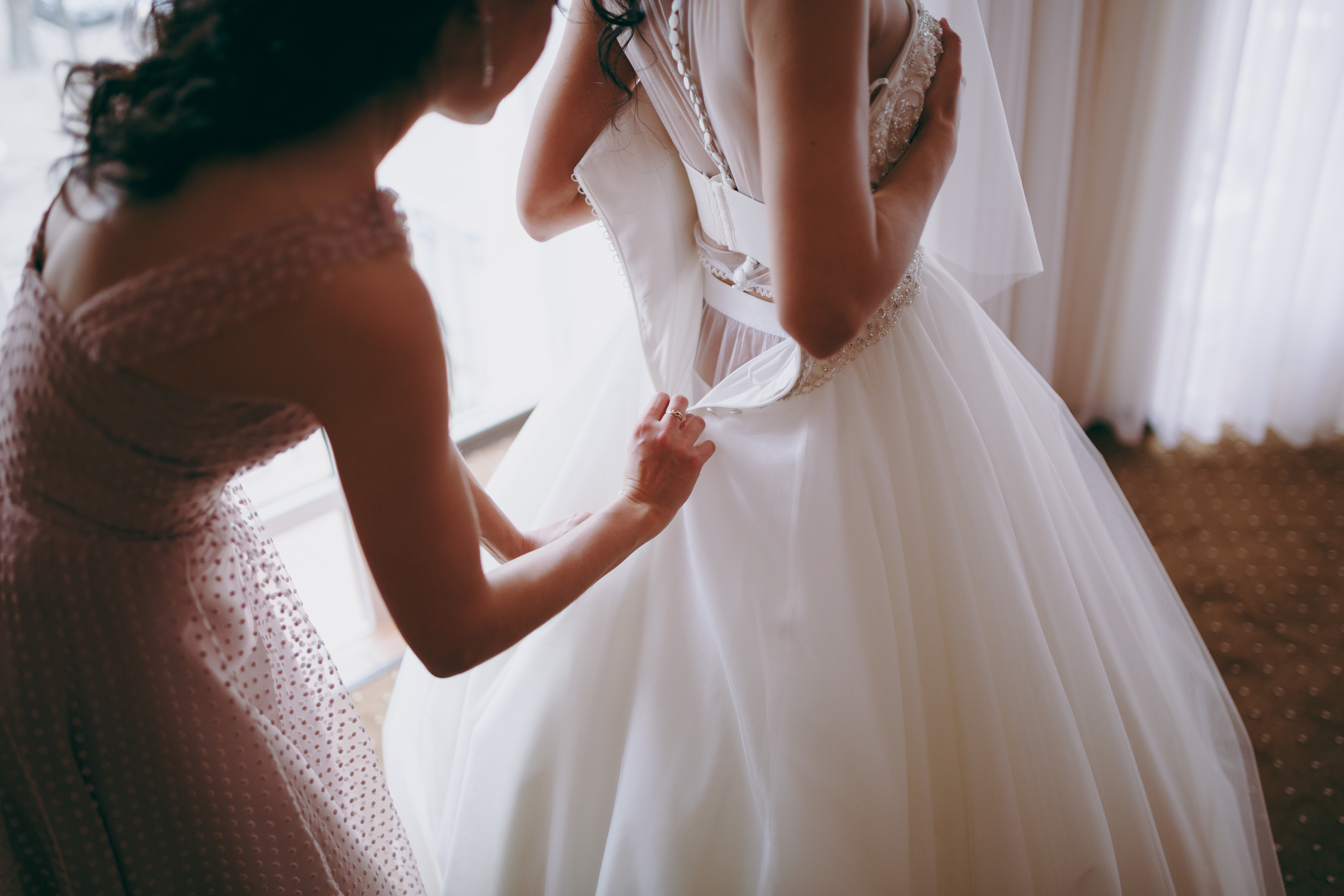 Maid of honor helping the bride into her dress. | Source: Shutterstock