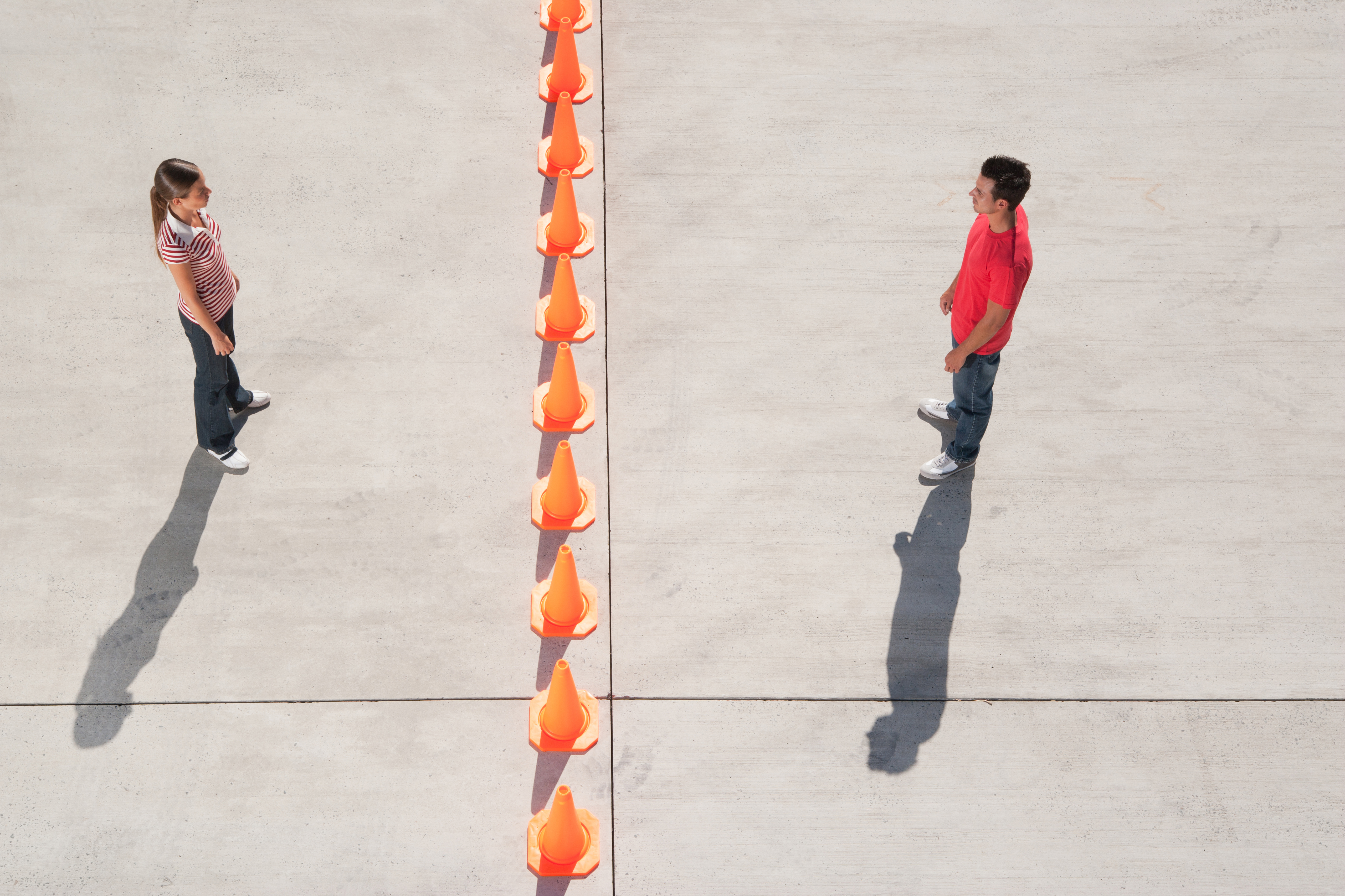 A couple standing on either side of a row of traffic cones | Source: Getty Images